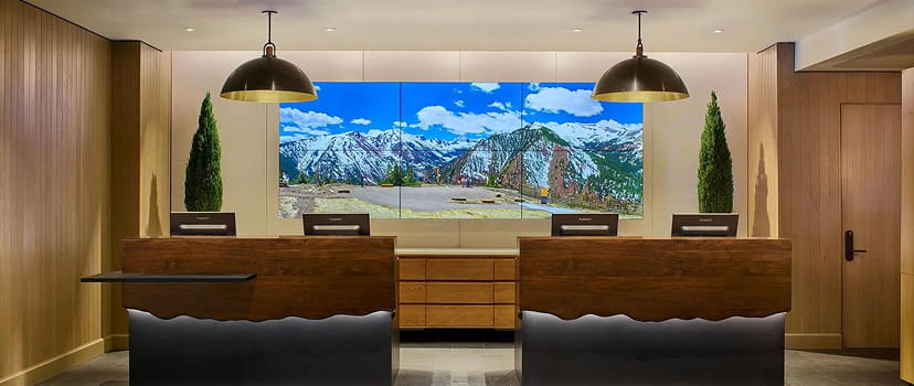 Wood-panelled reception and mountain photograph behind the front desk at Limelight Hotel Snowmass.