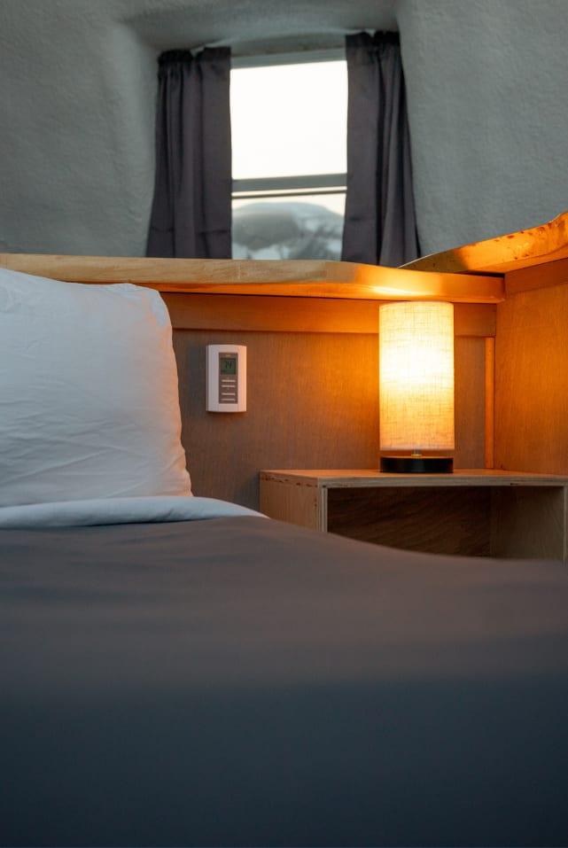 Cosy igloo interior with bed, timber cabinetry and a curved wall, Borealis Basecamp, Alaska, USA