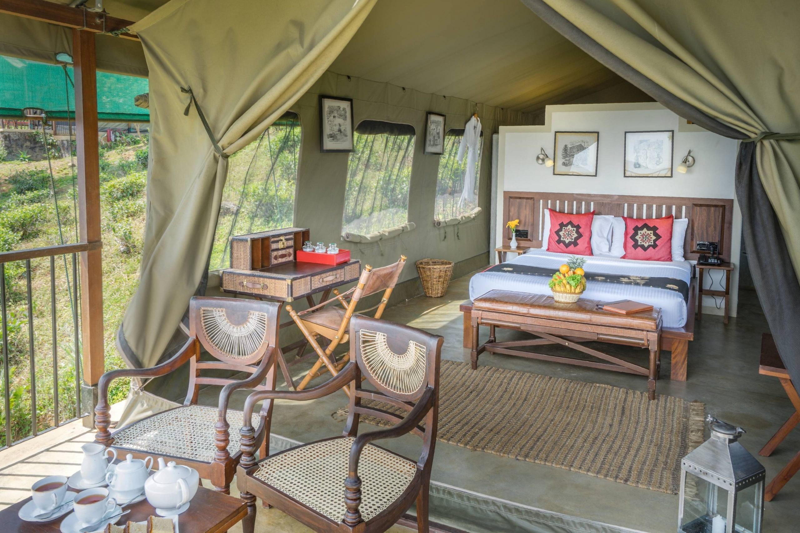 Canvas tent interior with wooden chairs, patterned cushions and mountain-facing windows at Madulkelle Tea and Eco Lodge