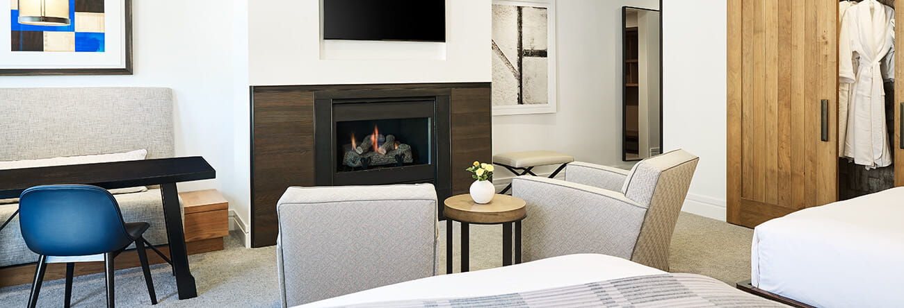 Town-side guest room with a fireplace, seating area, and beds at The Little Nell, Aspen, USA