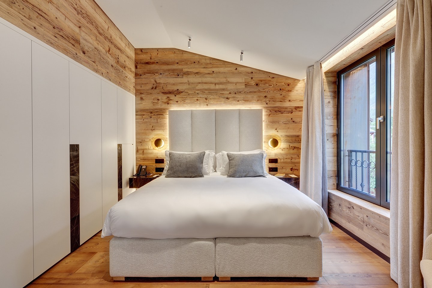Suite des Glaciers bedroom with pale wood walls and mountain-facing windows, Grand Hôtel des Alpes, Chamonix, France
