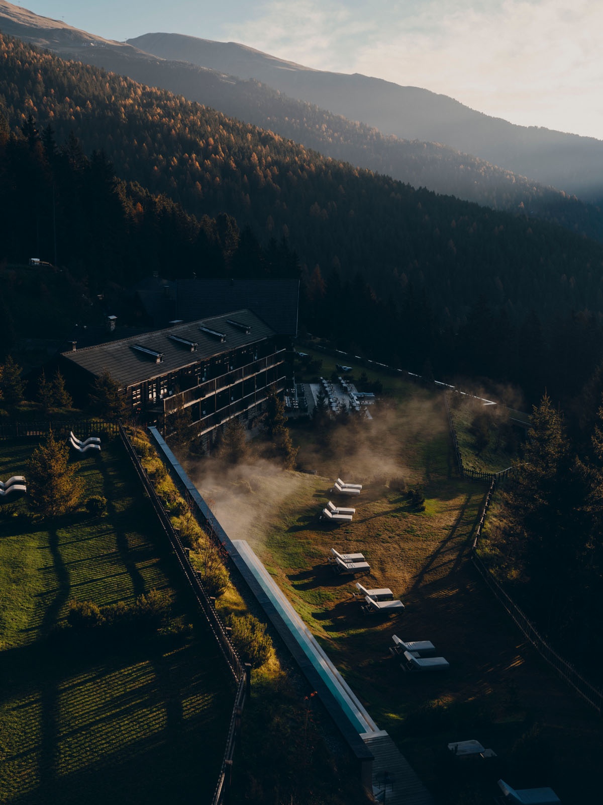 Elevated view of the FORESTIS property nestled among wooded mountain slopes, Dolomites, Italy