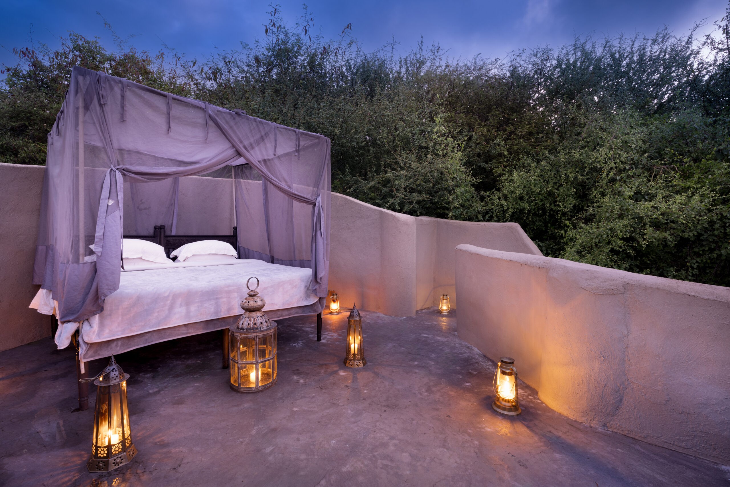 Outdoor canopy bed with lanterns on a rooftop terrace at Ol Donyo Lodge.