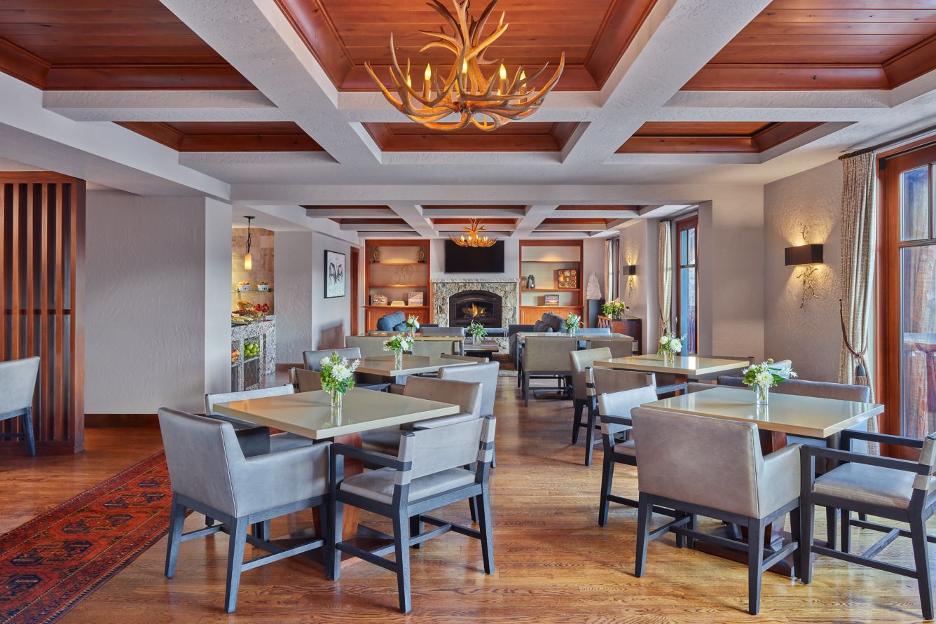Dining tables, timber ceiling and fireplace in the Club Lounge at The Ritz-Carlton, Bachelor Gulch.
