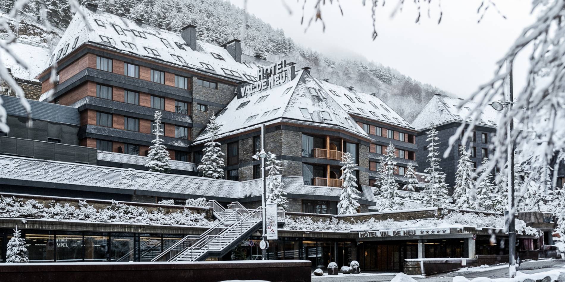 Hotel exterior surrounded by snow-covered buildings and mountains at Hotel Val de Neu, Baqueira-Beret, Spain