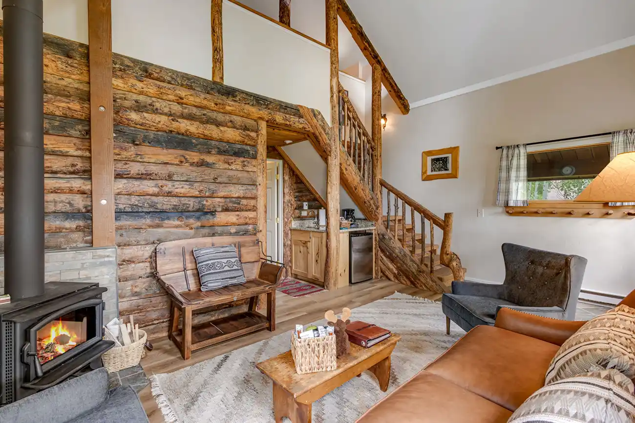 Log walls, a wood-burning stove and leather seating inside a cabin at Vista Verde Ranch, Clark, Colorado.