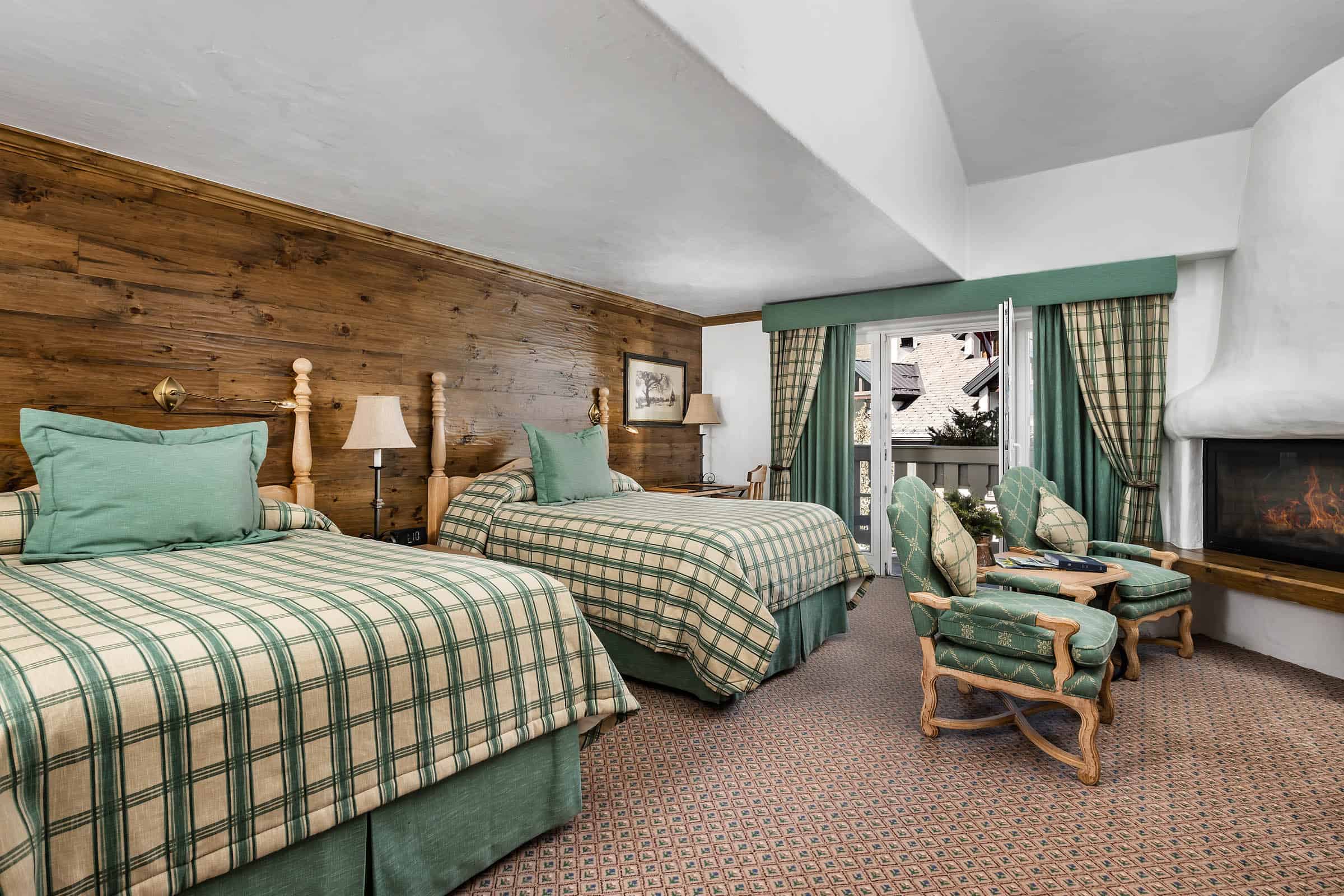 Guest room with two beds, chairs, fireplace and balcony at Sonnenalp Vail, Vail, USA