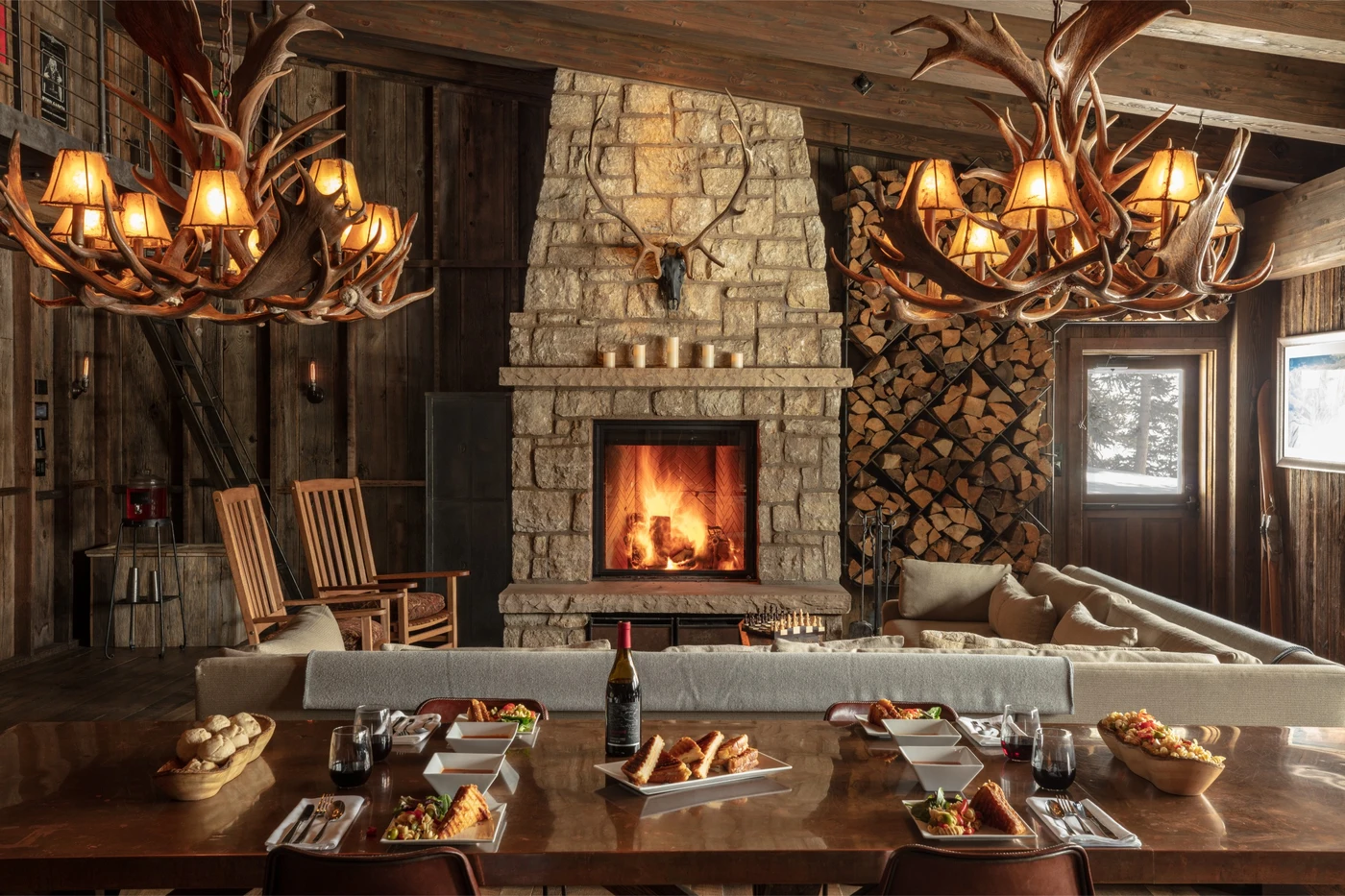 Eleven Scarp Ridge Lodge lounge with a stone fireplace and set dining table, Crested Butte, USA
