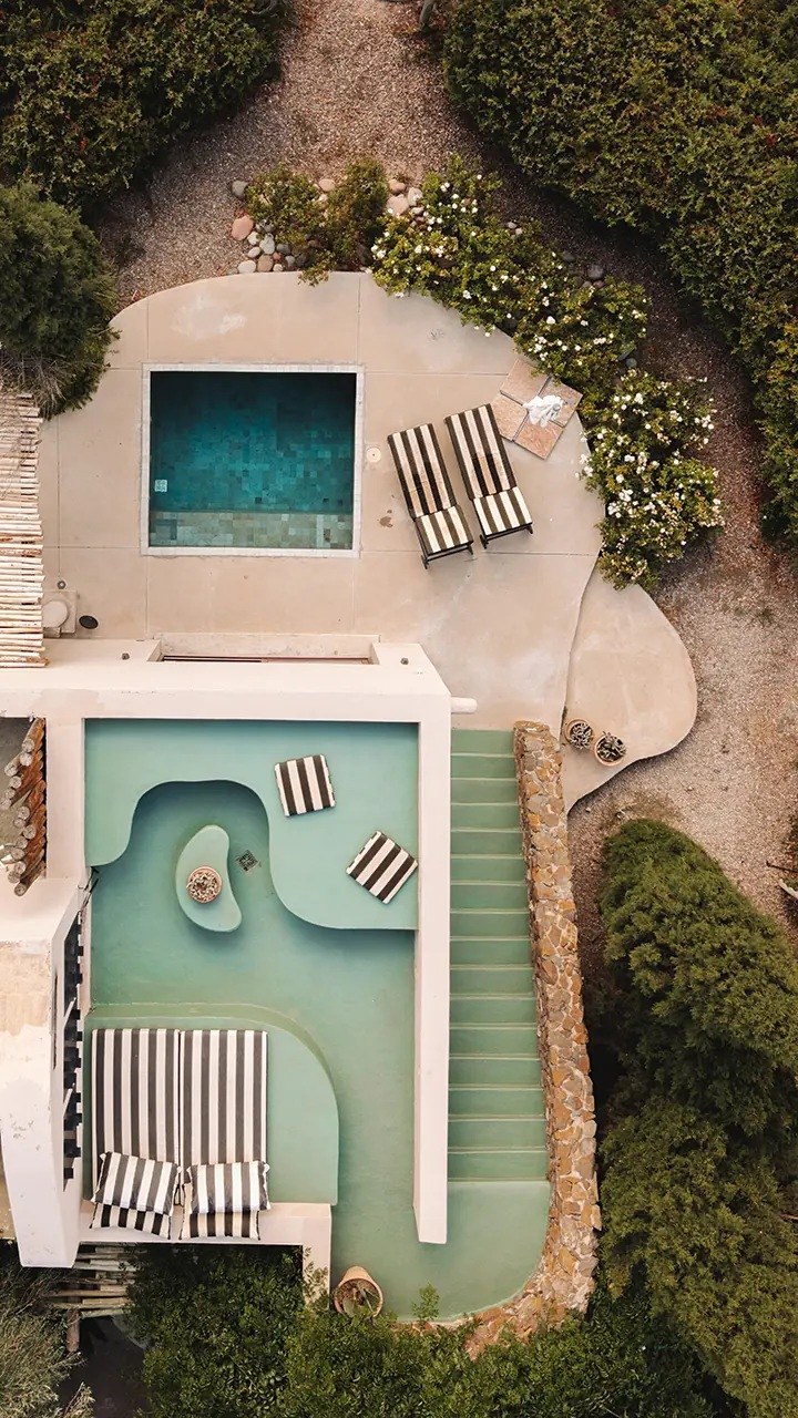 Overhead view of two private plunge pools, striped loungers and pale villa terraces, Cavas Wine Lodge