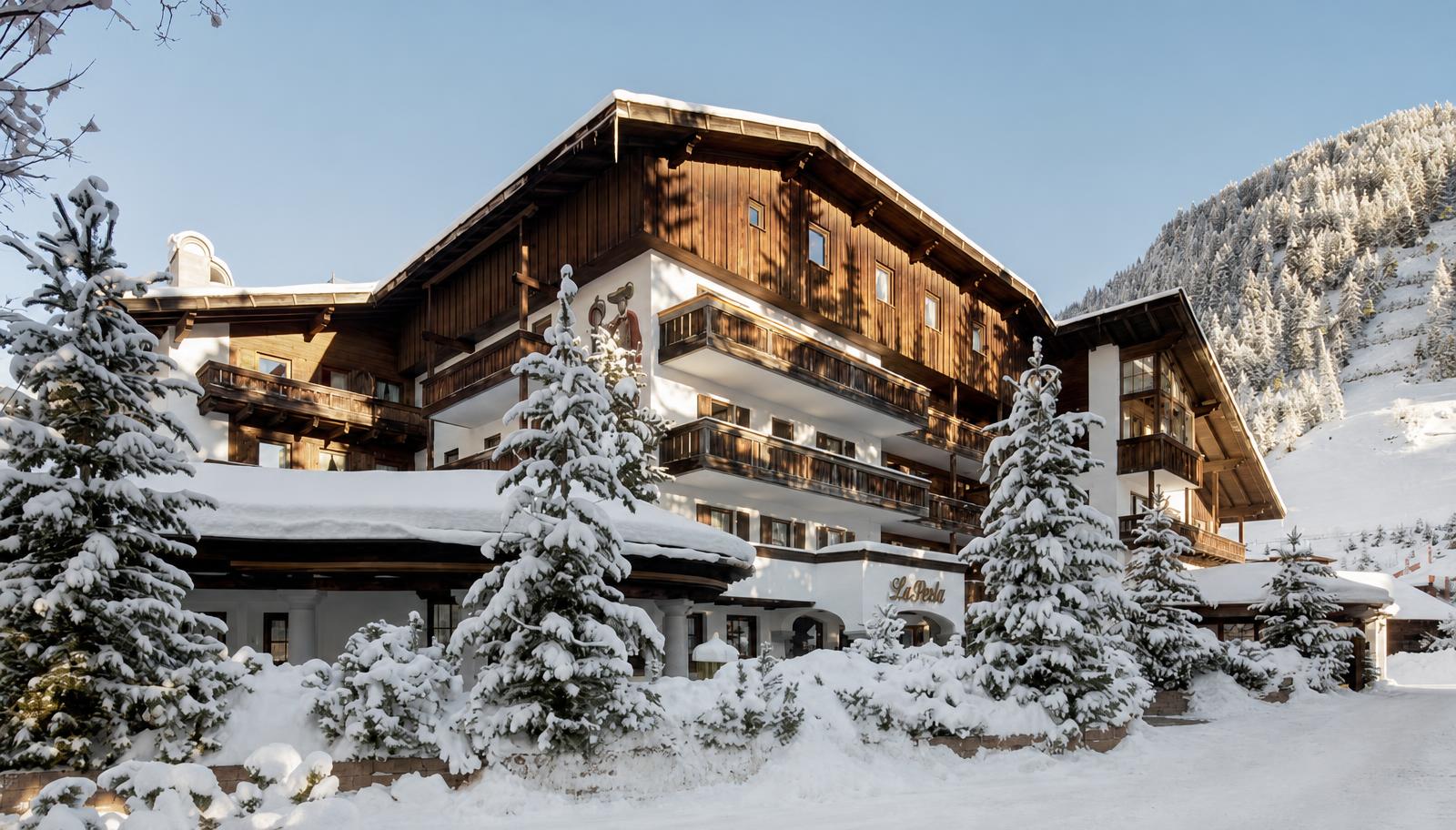 Hotel La Perla’s timber-clad exterior among snow-covered trees in Corvara