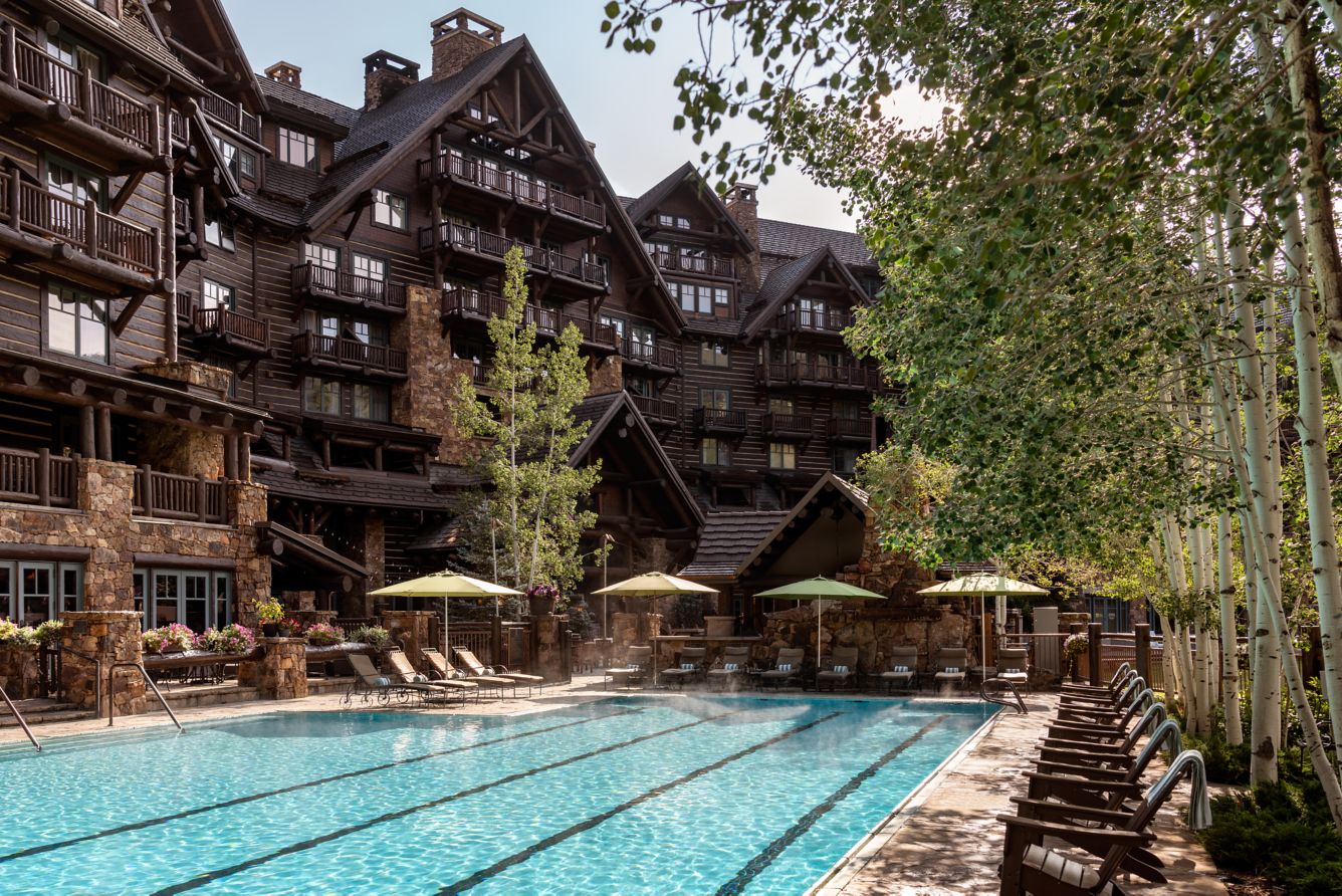 Summer swimming pool and sun loungers beneath the timber balconies of The Ritz-Carlton, Bachelor Gulch.