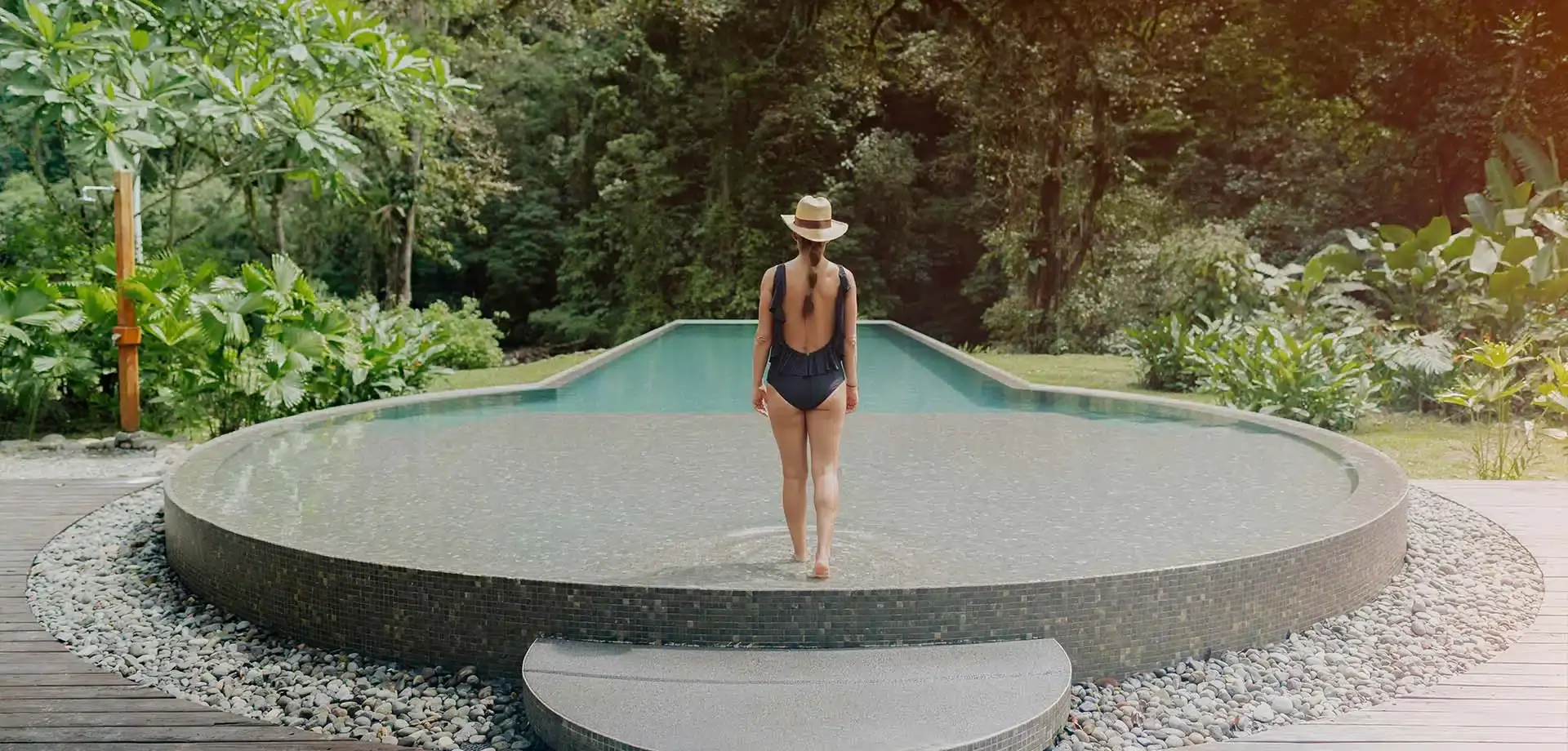 Guest beside a curved infinity pool surrounded by rainforest, Pacuare Lodge, Pacuare River, Costa Rica