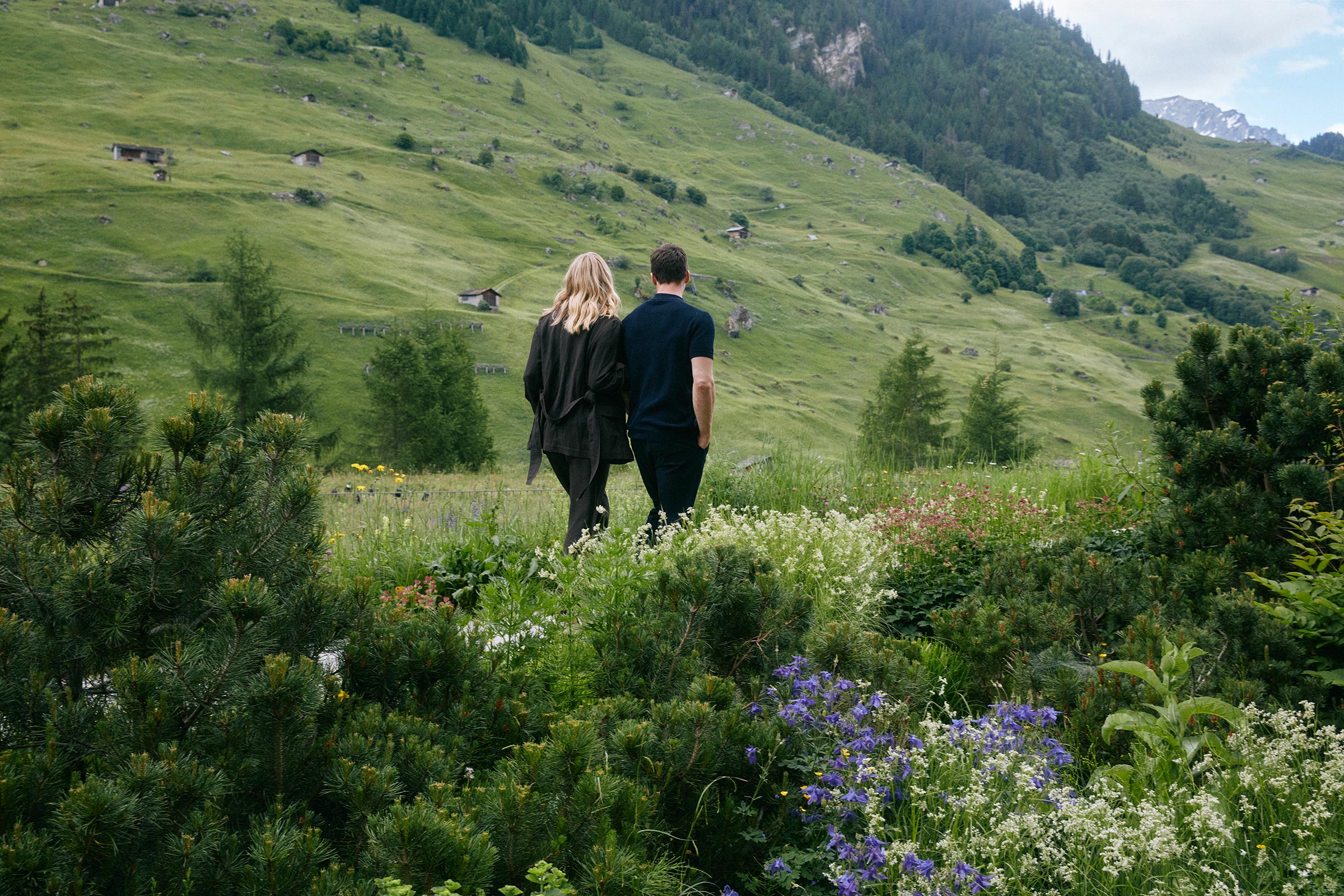 Two people walking through a flower-filled Alpine meadow at 7132 Hotel, Vals, Switzerland