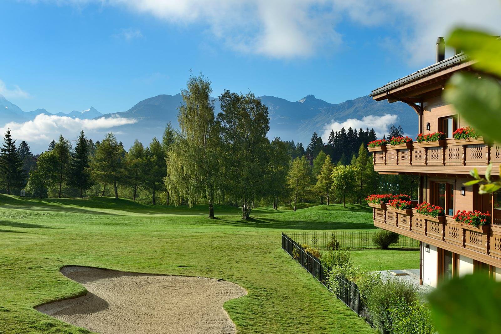Hotel exterior beside the golf fairway and bunker with Alpine backdrop, Guarda Golf Hotel & Residences, Crans-Montana, Switzerland