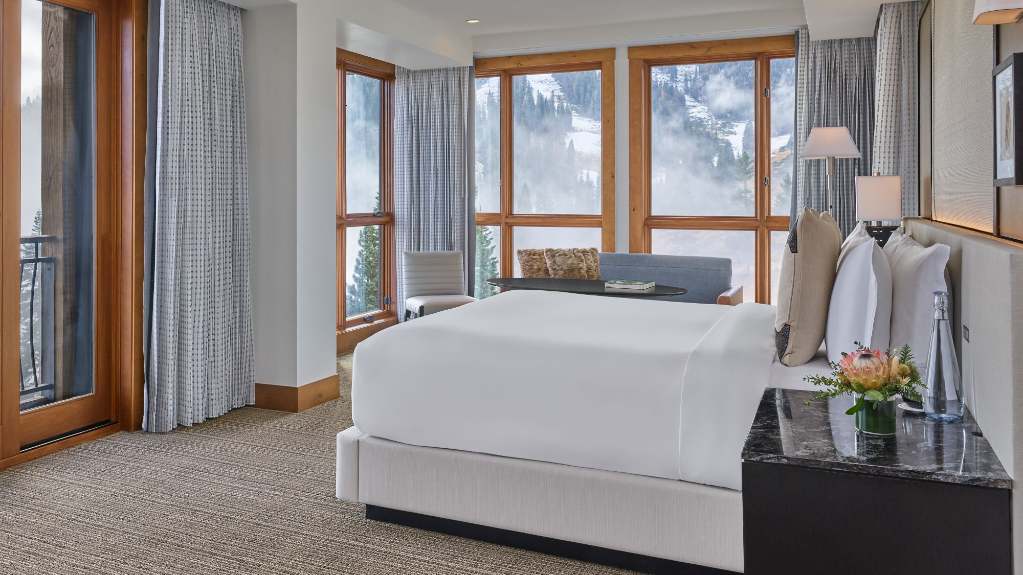 King bedroom with large windows and forest views at The Ritz-Carlton, Lake Tahoe, Northstar, USA