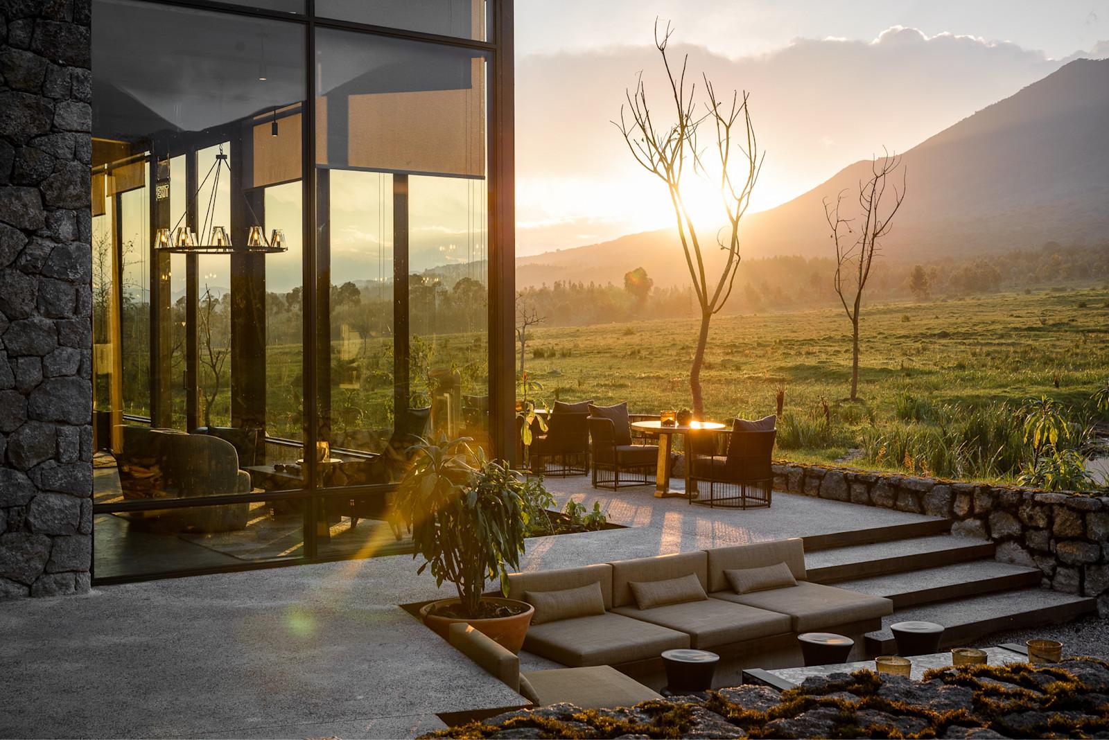 Stone lodge exterior and terrace at sunrise with mountain views, Singita Kwitonda Lodge, Volcanoes National Park, Rwanda