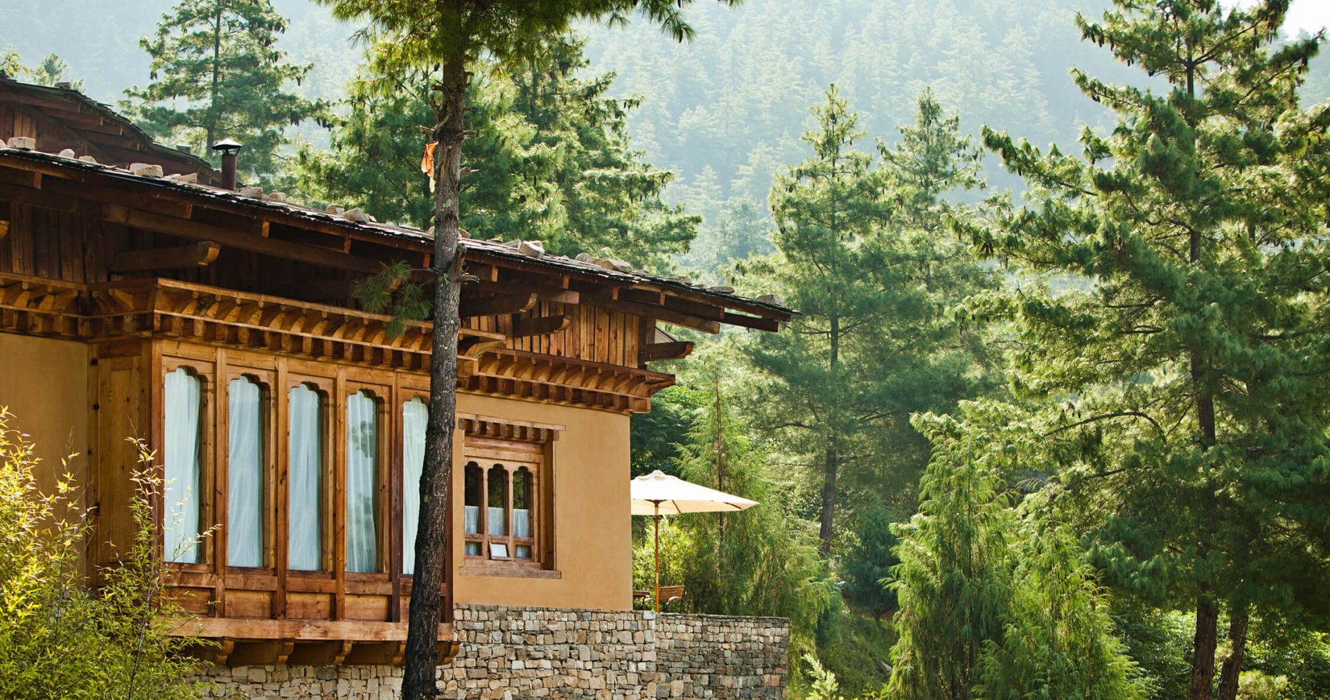 Bhutanese-style villa exterior among pine trees at COMO Uma Paro, Paro, Bhutan