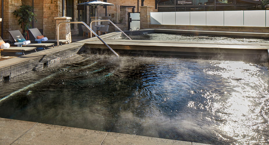 Steaming outdoor spa pool surrounded by snowy terraces at Limelight Hotel Snowmass.