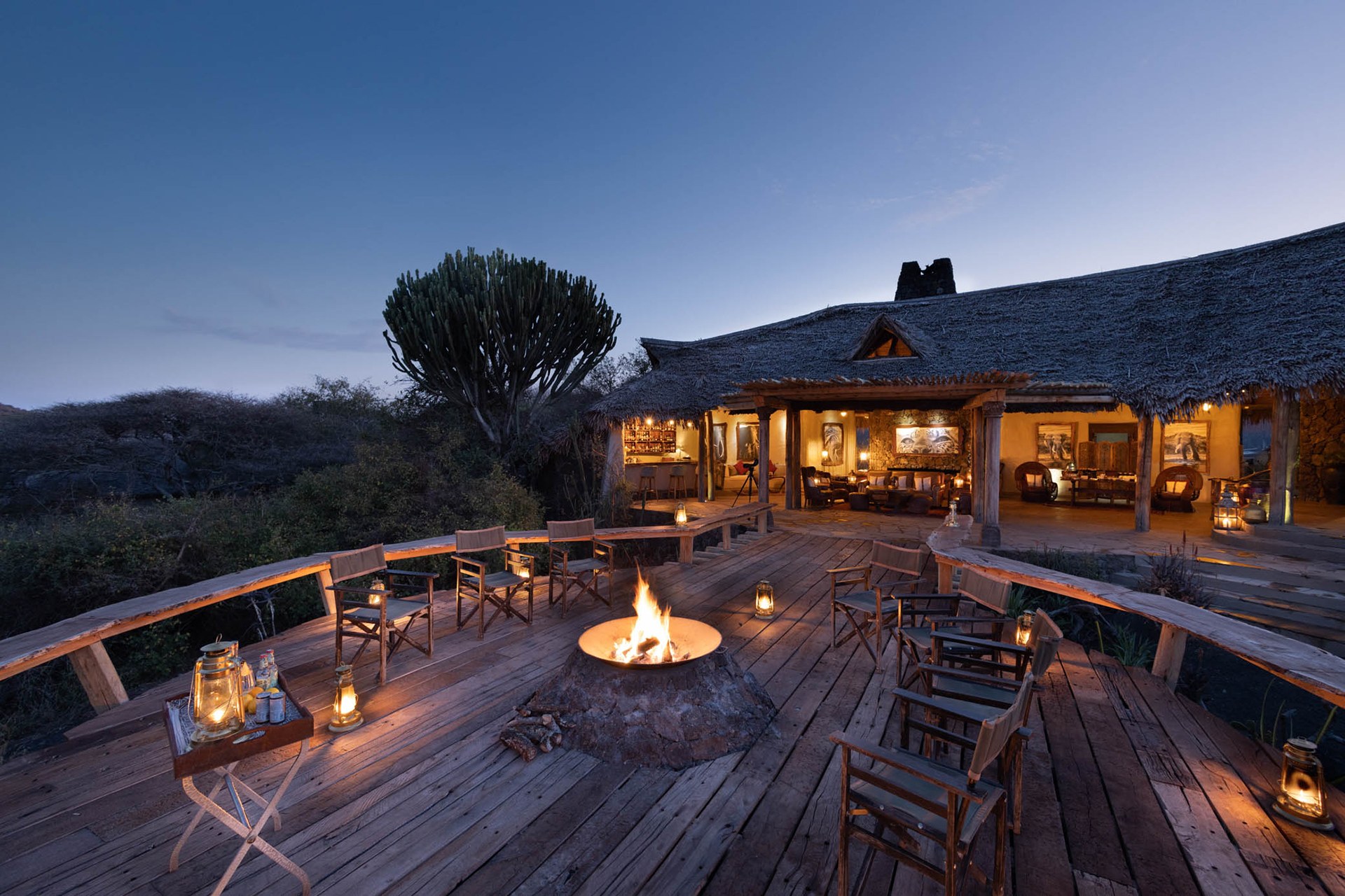 Lantern-lit lodge terrace and fire pit at dusk at Ol Donyo Lodge.