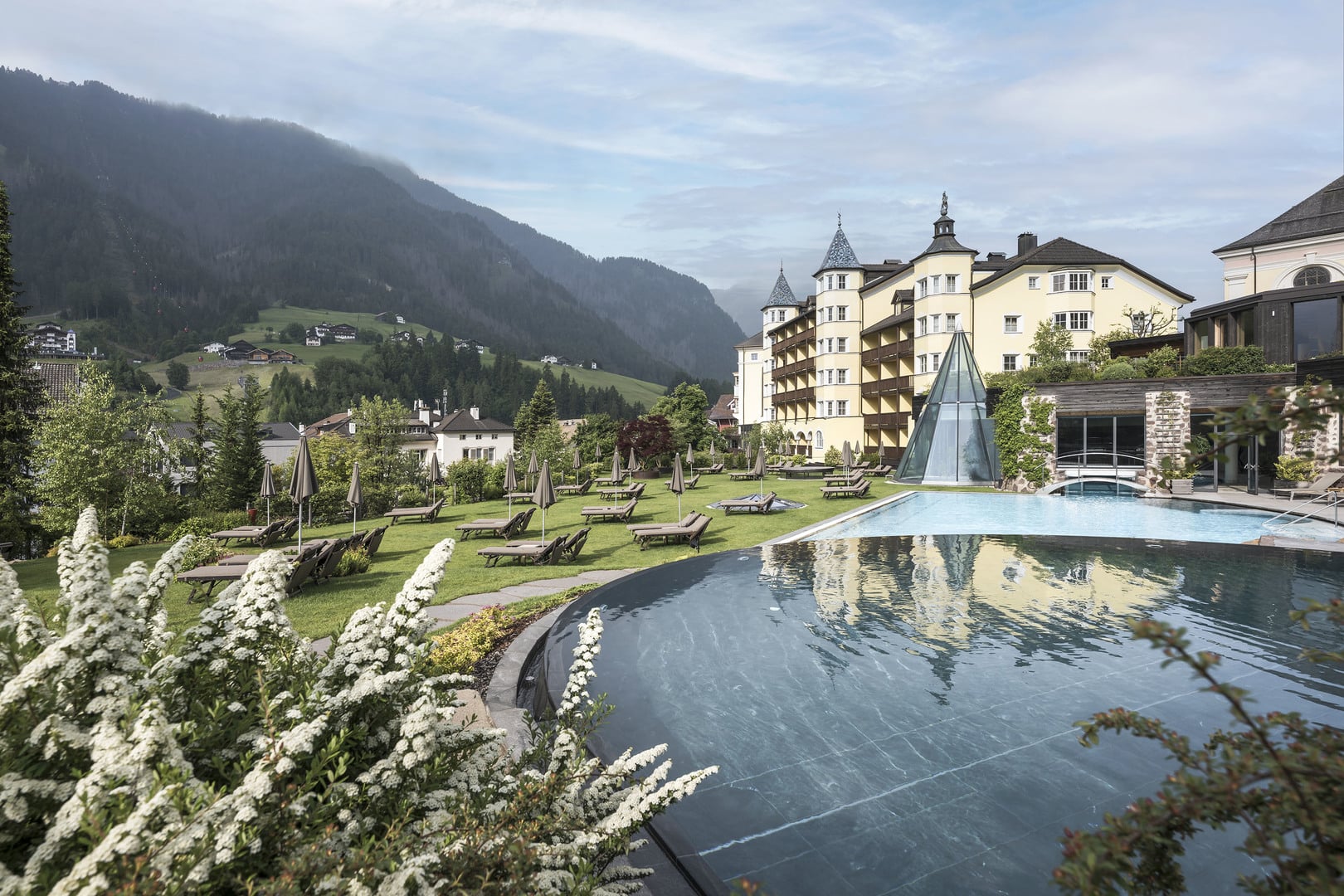 Hotel exterior and pool in summer mountain setting, ADLER Spa Resort Dolomiti, Ortisei, Italy
