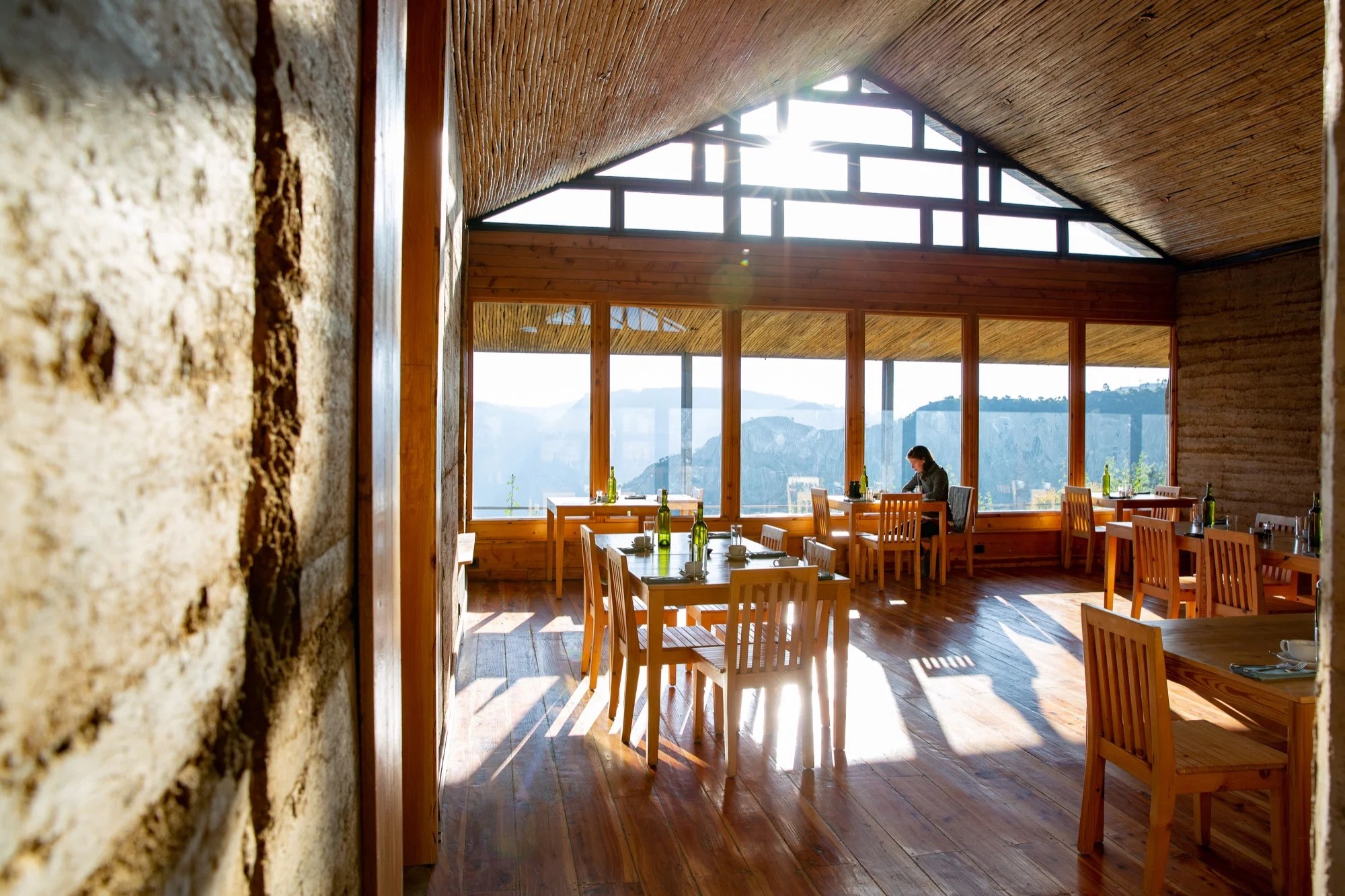 Sunlit dining room with timber tables and large windows facing the mountains, Limalimo Lodge