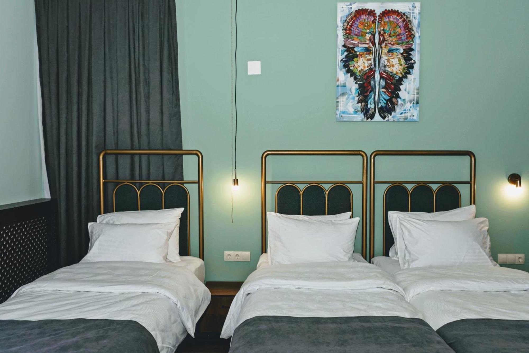 Twin guest room with pale blue walls and dark curtains at Paliani Hotel, Mestia, Georgia