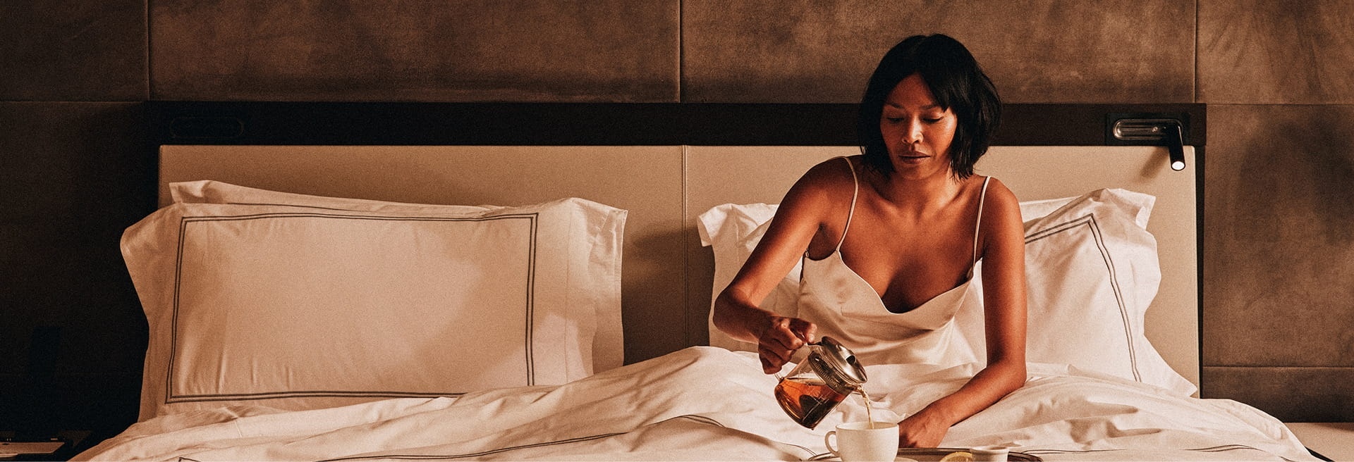 Guest sitting in bed with a breakfast tray at The Little Nell, Aspen, USA