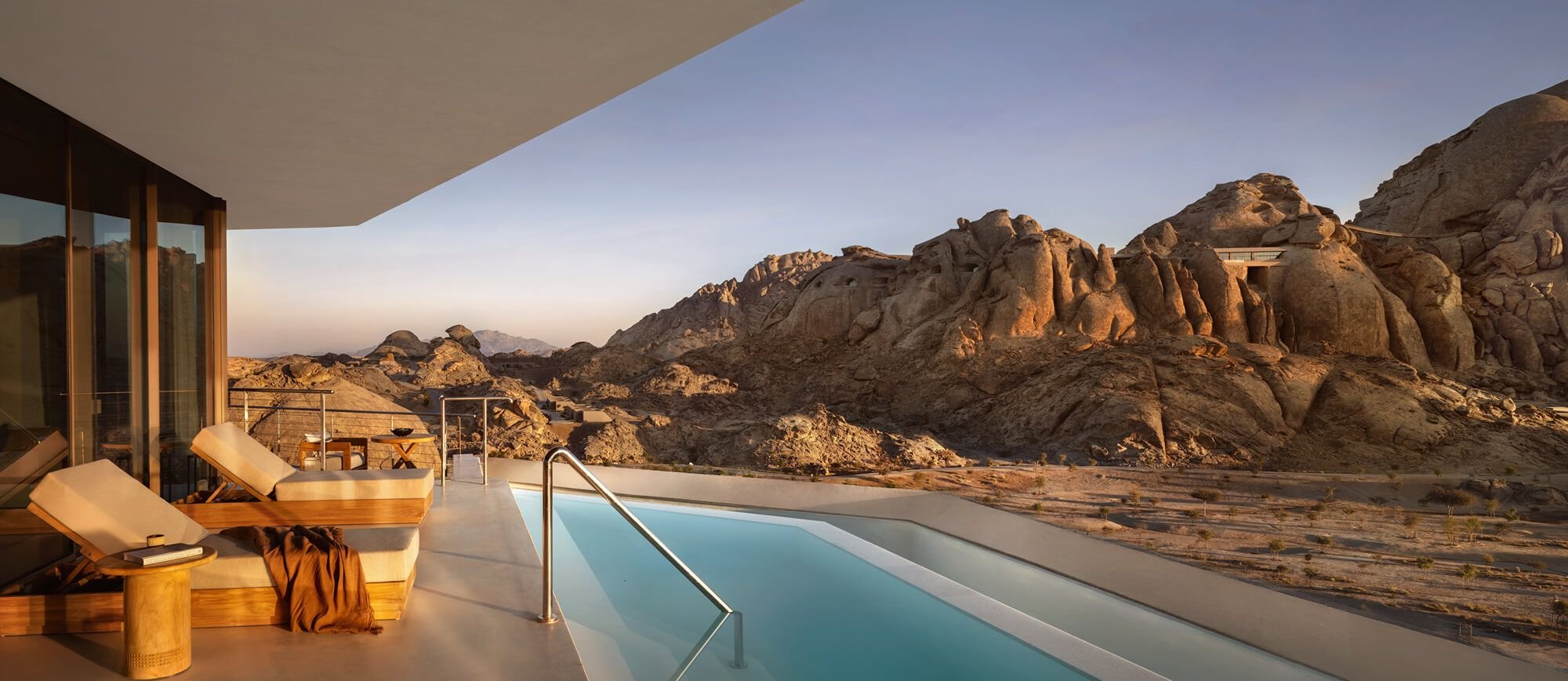 A private villa pool at Desert Rock set against the granite boulders of the Hejaz Mountains