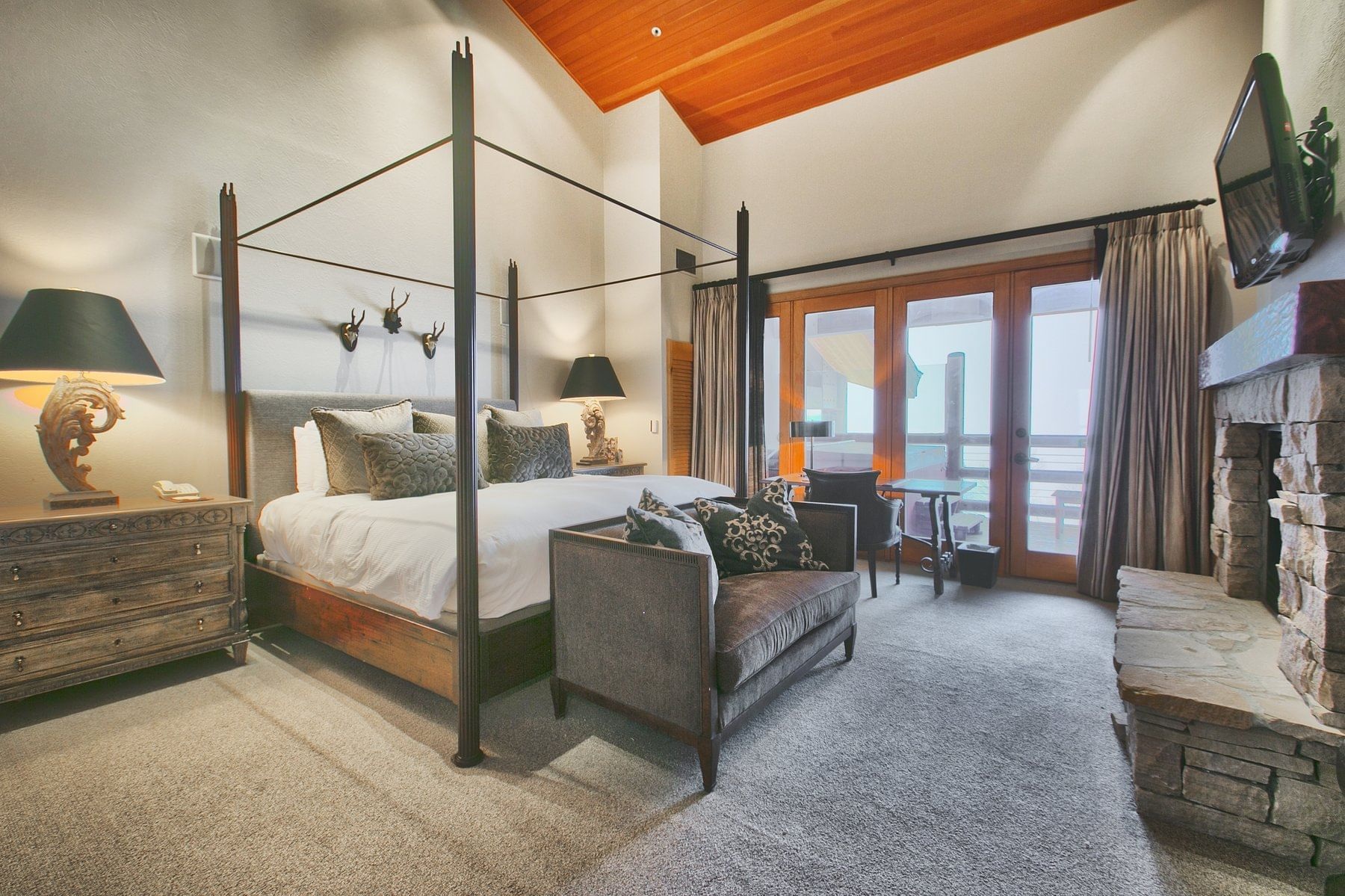 Guest bedroom with stone fireplace and balcony doors at Stein Eriksen Lodge, Deer Valley, USA