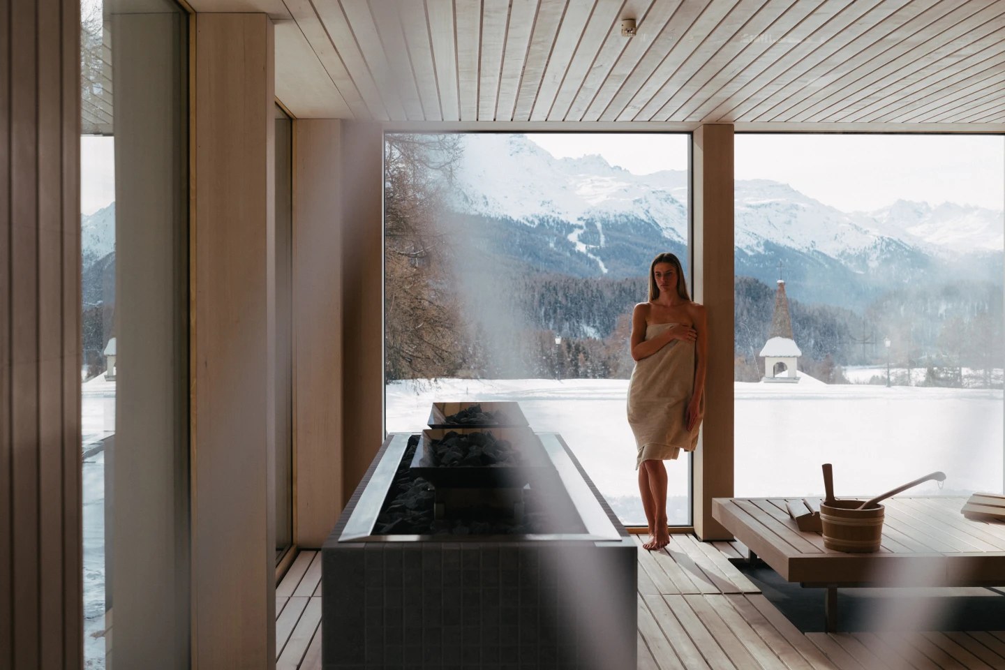 Guest in the timber sauna beside a mountain-view window, Suvretta House, St. Moritz, Switzerland