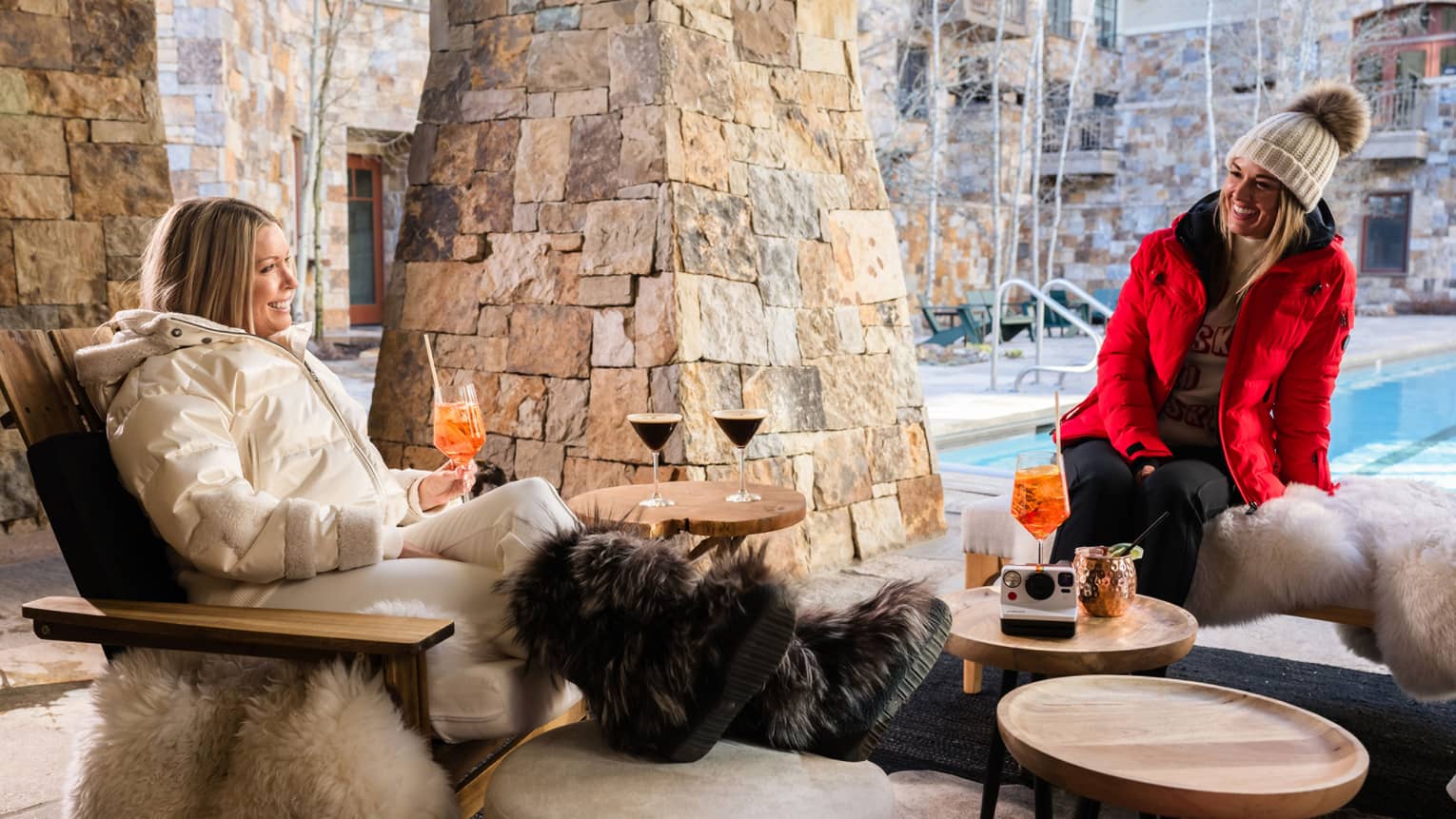 Guests relaxing beside the stone fireplace on the pool terrace at Four Seasons Resort Vail.