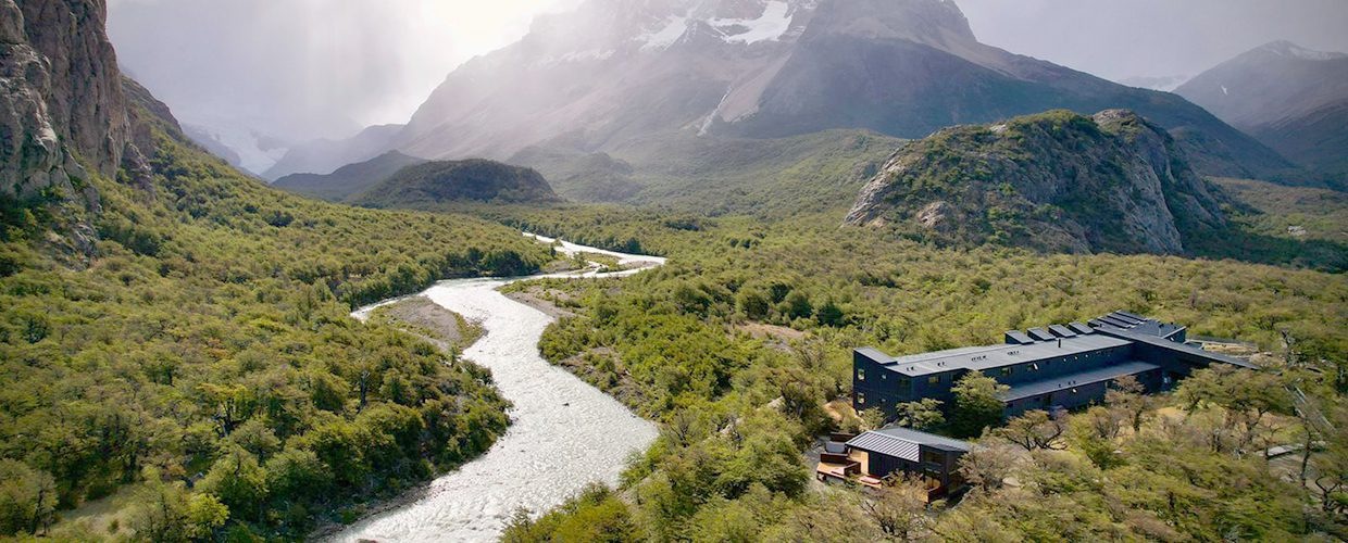 Wide view of the lodge beside a river beneath the Andes at Explora El Chaltén, Patagonia, Argentina