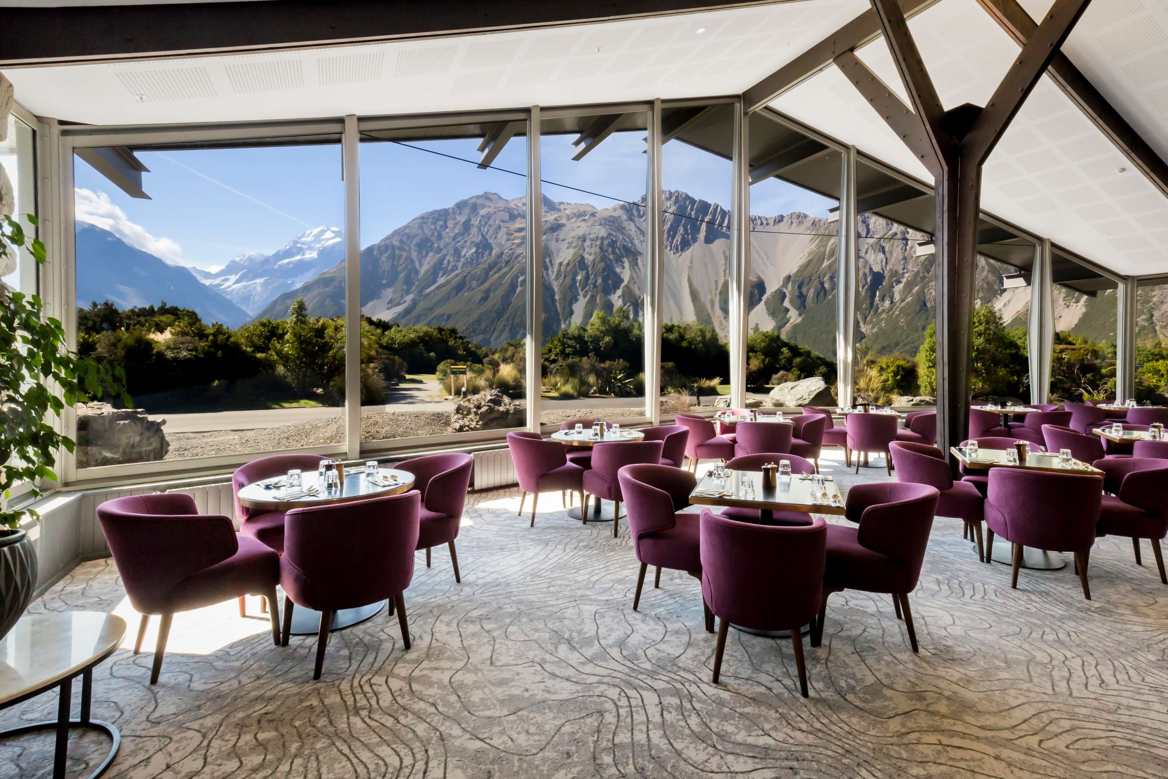 Mountain-facing dining room with purple chairs and panoramic windows at The Hermitage Hotel, Aoraki/Mount Cook, New Zealand