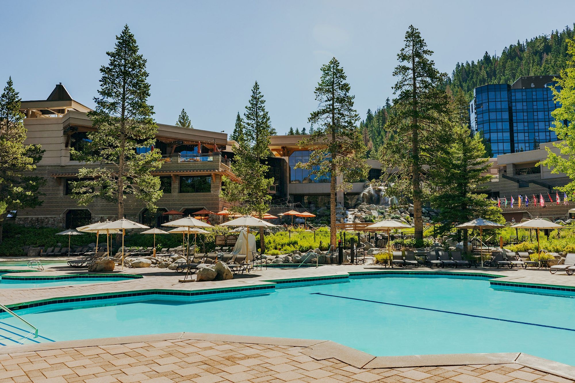 Outdoor swimming pool surrounded by resort buildings and trees at Everline Resort & Spa, Palisades Tahoe, USA