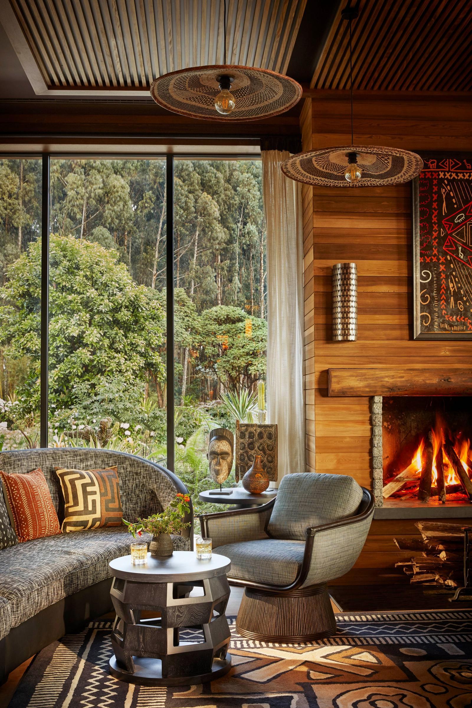 Fireplace lounge with armchairs and forest views, One&Only Gorilla's Nest, Volcanoes National Park, Rwanda
