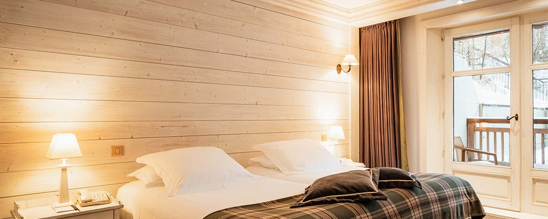 Classic room with wood panelling and balcony door at Les Barmes de l'Ours, Val d'Isère, France