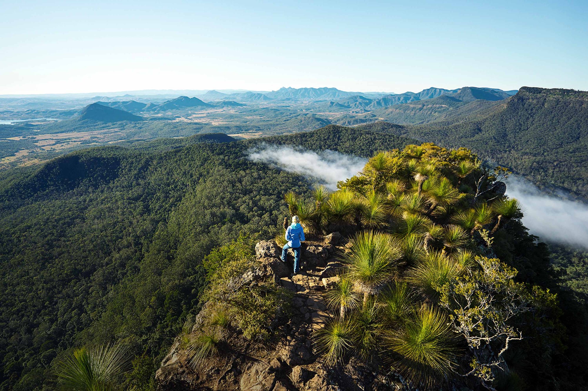 Hikers on a rocky Scenic Rim lookout near Spicers Peak Lodge