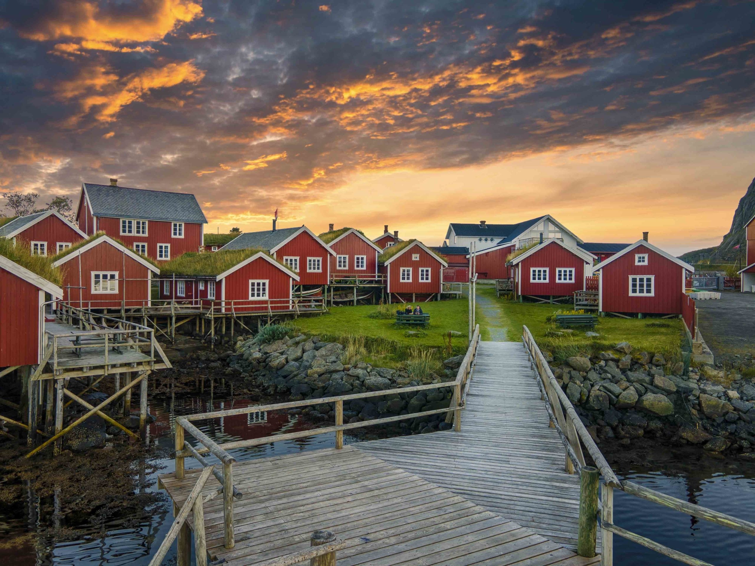 Red waterfront cabins and wooden walkways at sunset at Reine Rorbuer, Reine, Norway