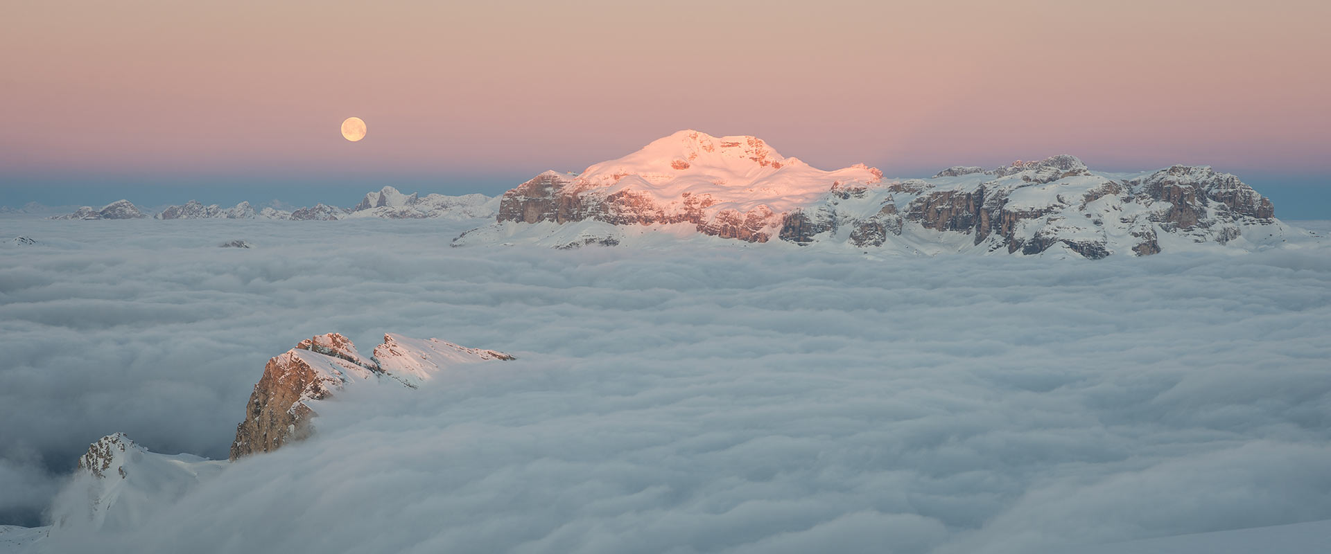 Moonrise over the snow-covered Dolomites above a sea of cloud, seen from Rifugio Lagazuoi