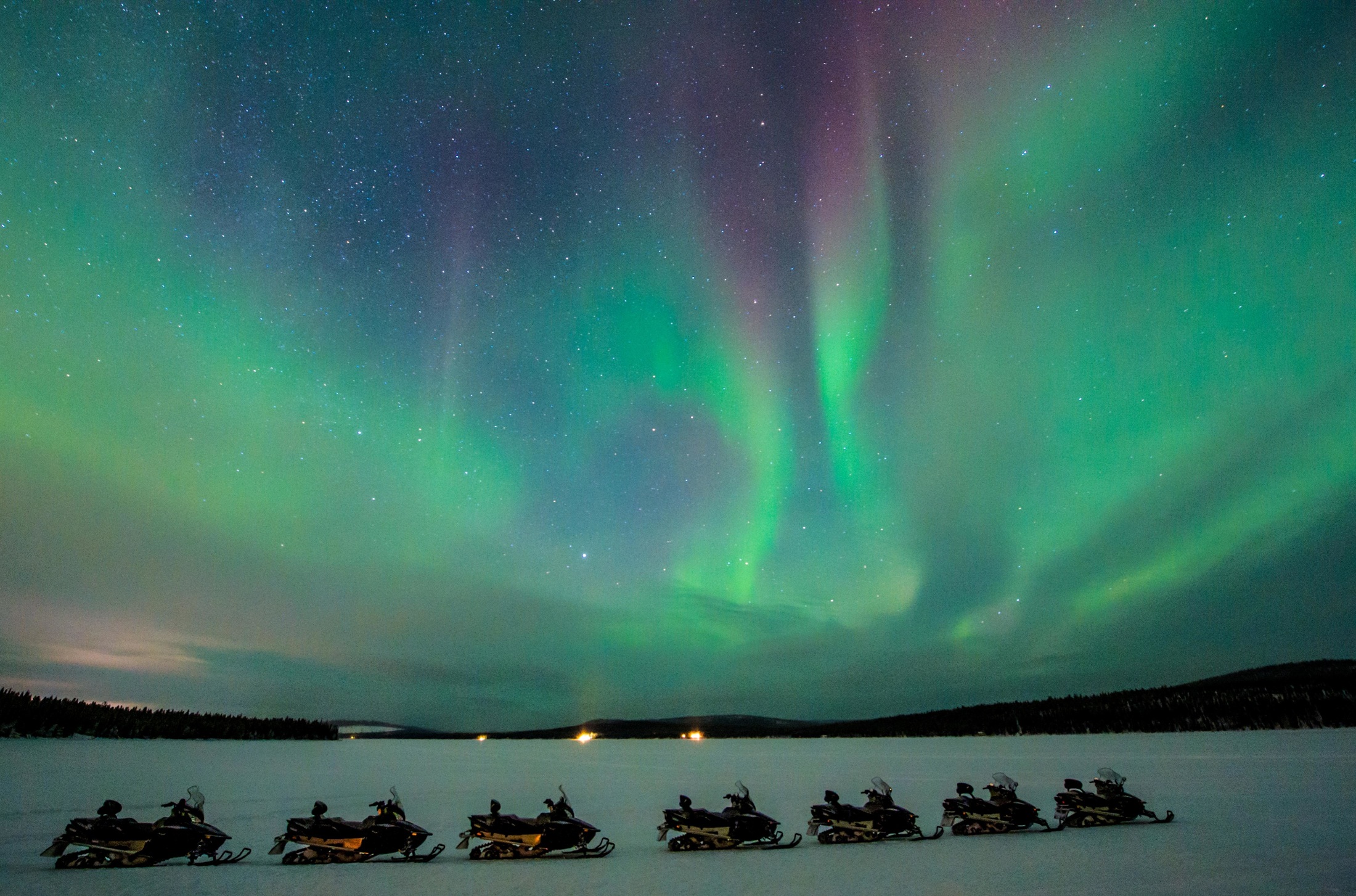 Northern lights above the snowy riverside landscape at Icehotel, Jukkasjärvi, Swedish Lapland