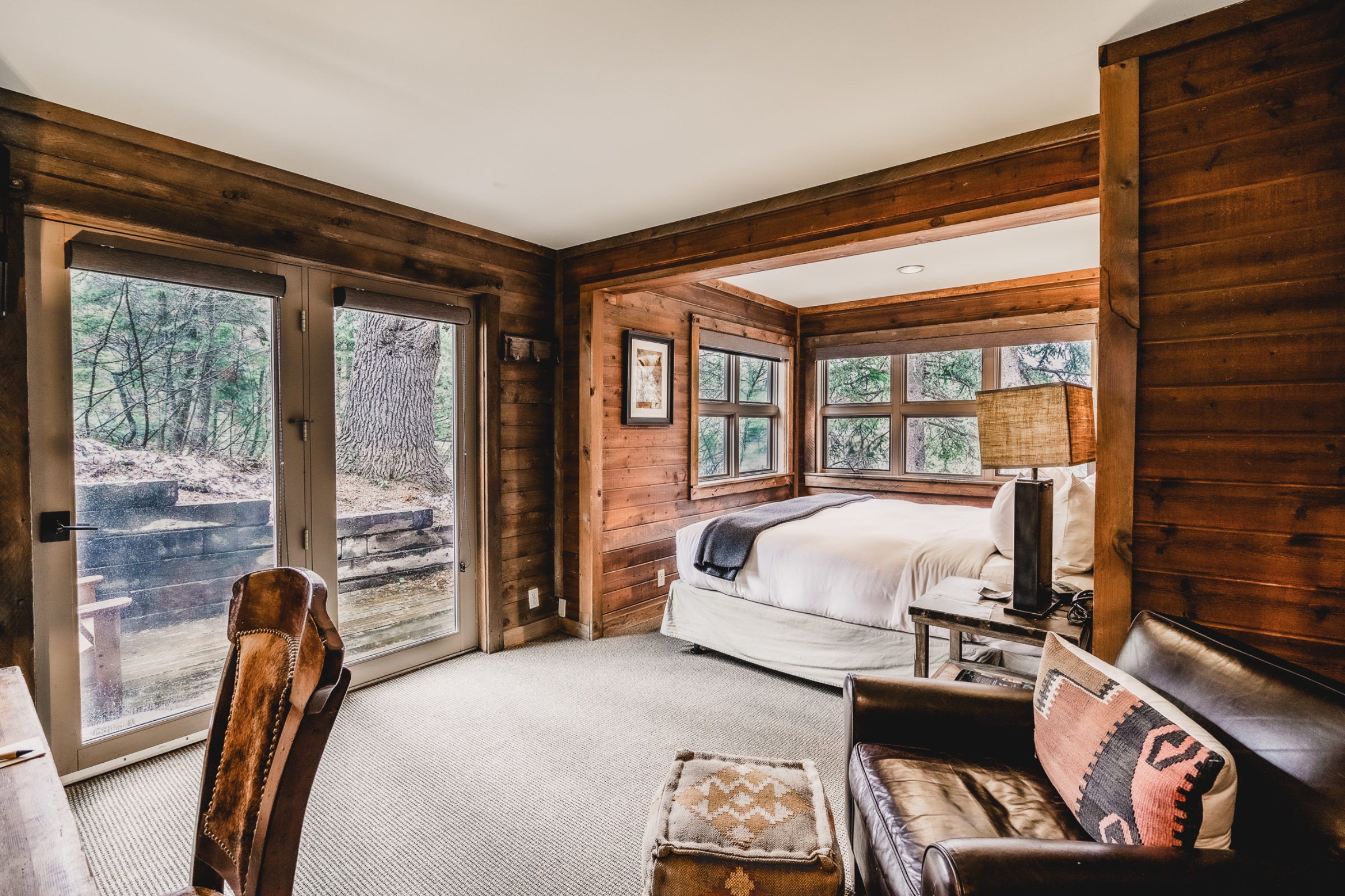Wood-panelled cottage bedroom with forest-facing windows at Sundance Mountain Resort, Sundance, USA