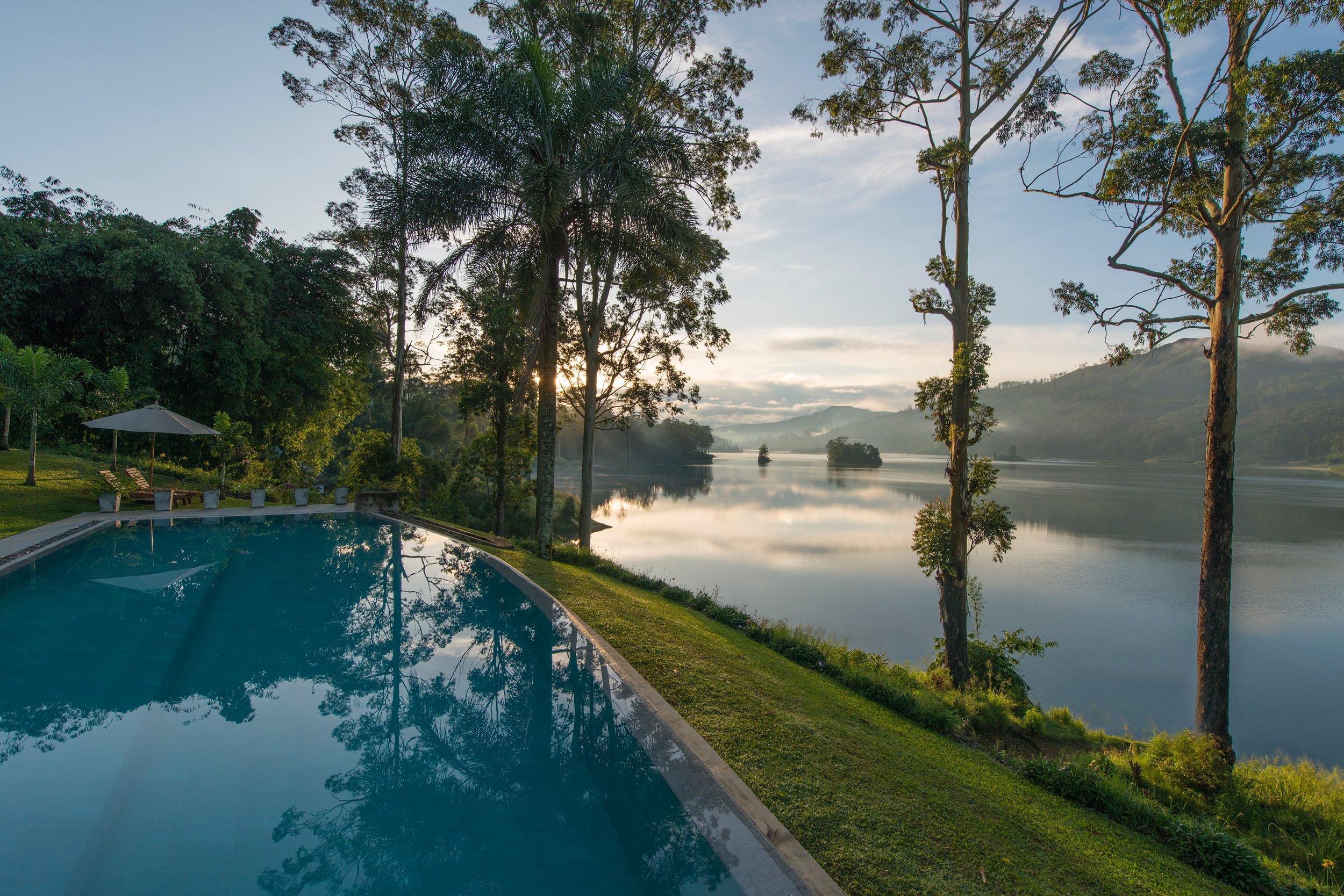 Lakeside swimming pool framed by tall trees in the morning mist, Ceylon Tea Trails, Hatton, Sri Lanka