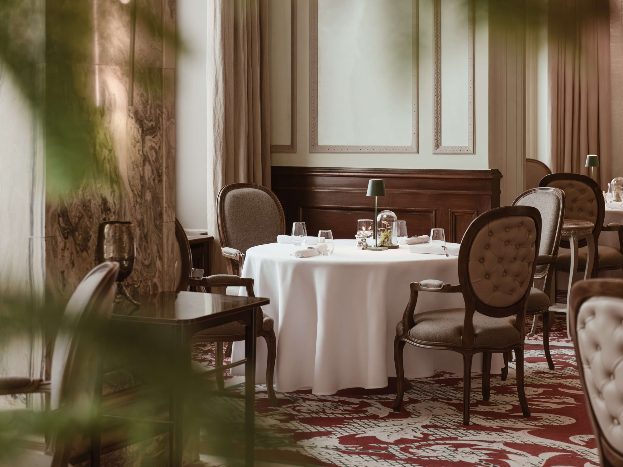 White-clothed dining tables and upholstered chairs in a wood-panelled restaurant, Carlton Hotel St. Moritz, St. Moritz, Switzerland