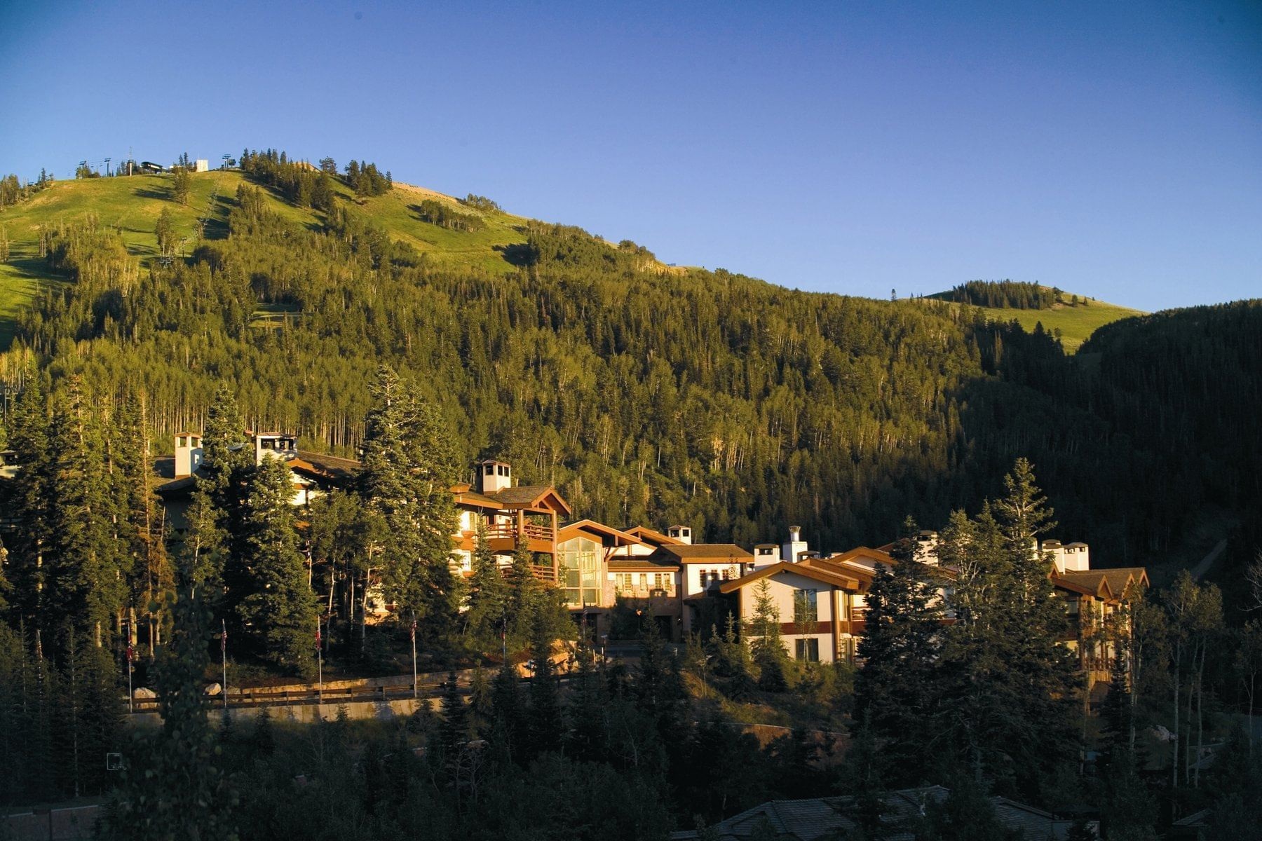 Summer lodge exterior below wooded alpine slopes at Stein Eriksen Lodge, Deer Valley, USA