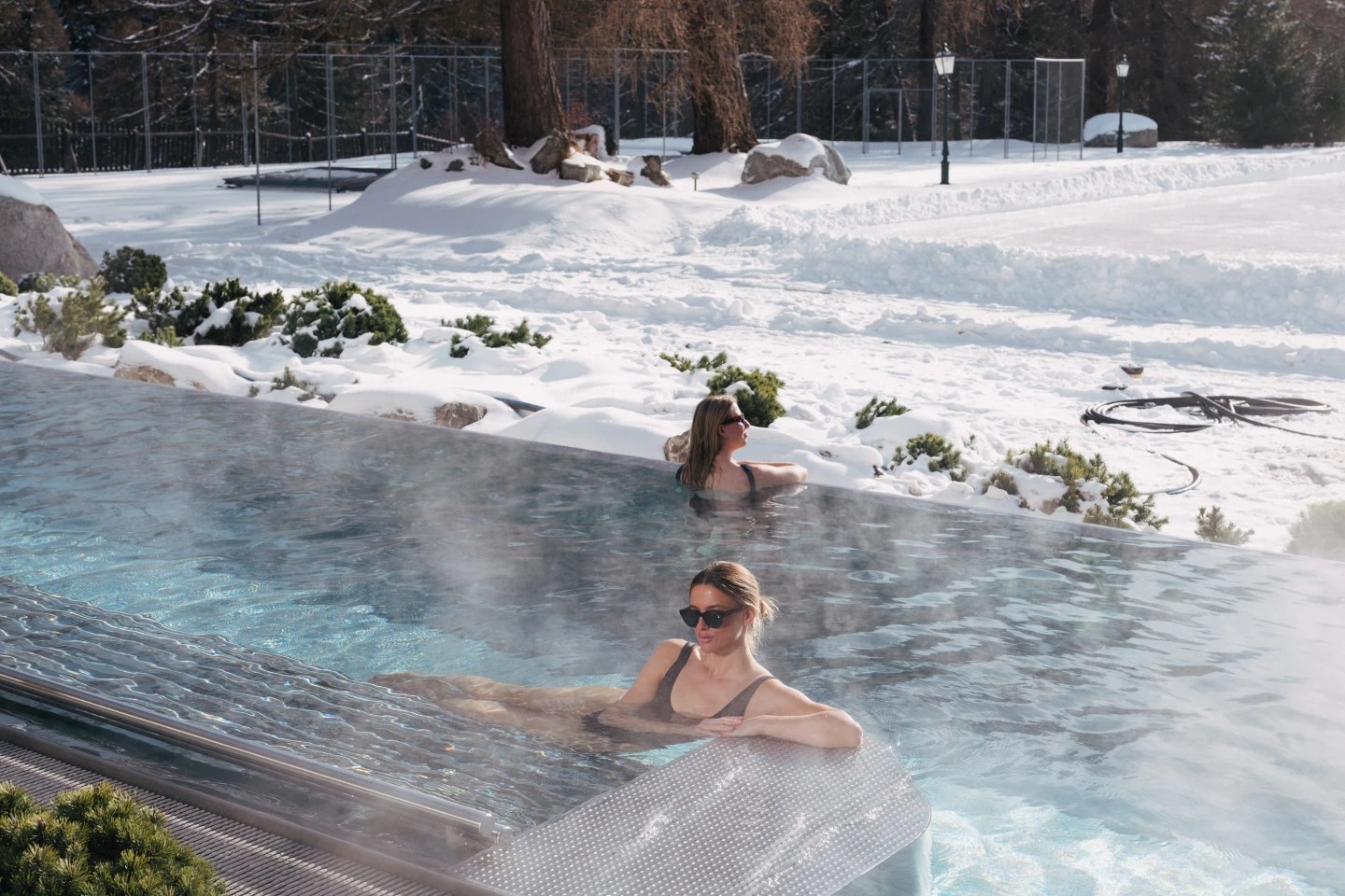 Guests in the steaming outdoor pool beside snowy grounds, Suvretta House, St. Moritz, Switzerland