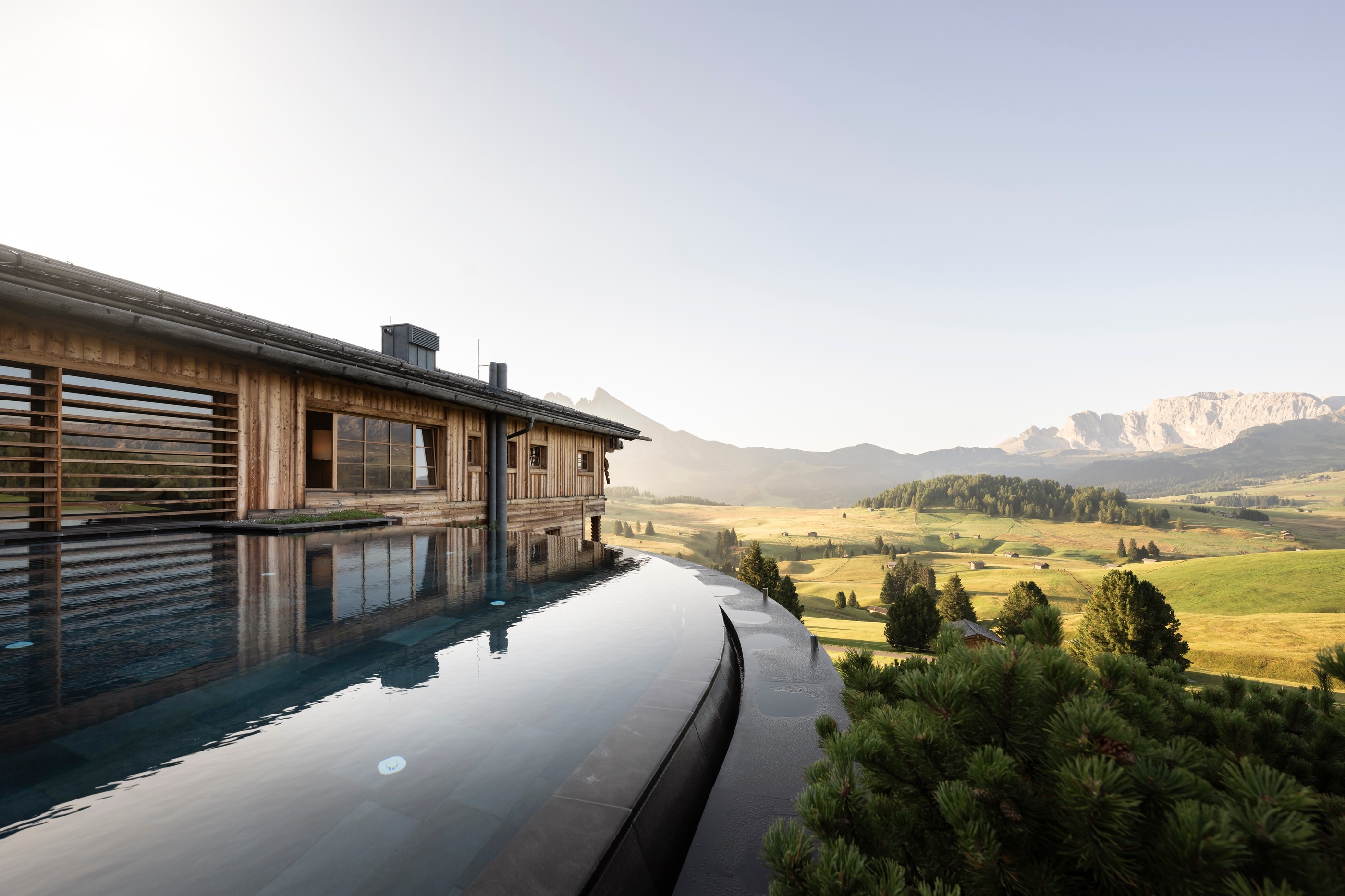 Outdoor infinity pool beside the timber lodge with mountain views at Adler Mountain Lodge, Alpe di Siusi (Seiser Alm), Italy