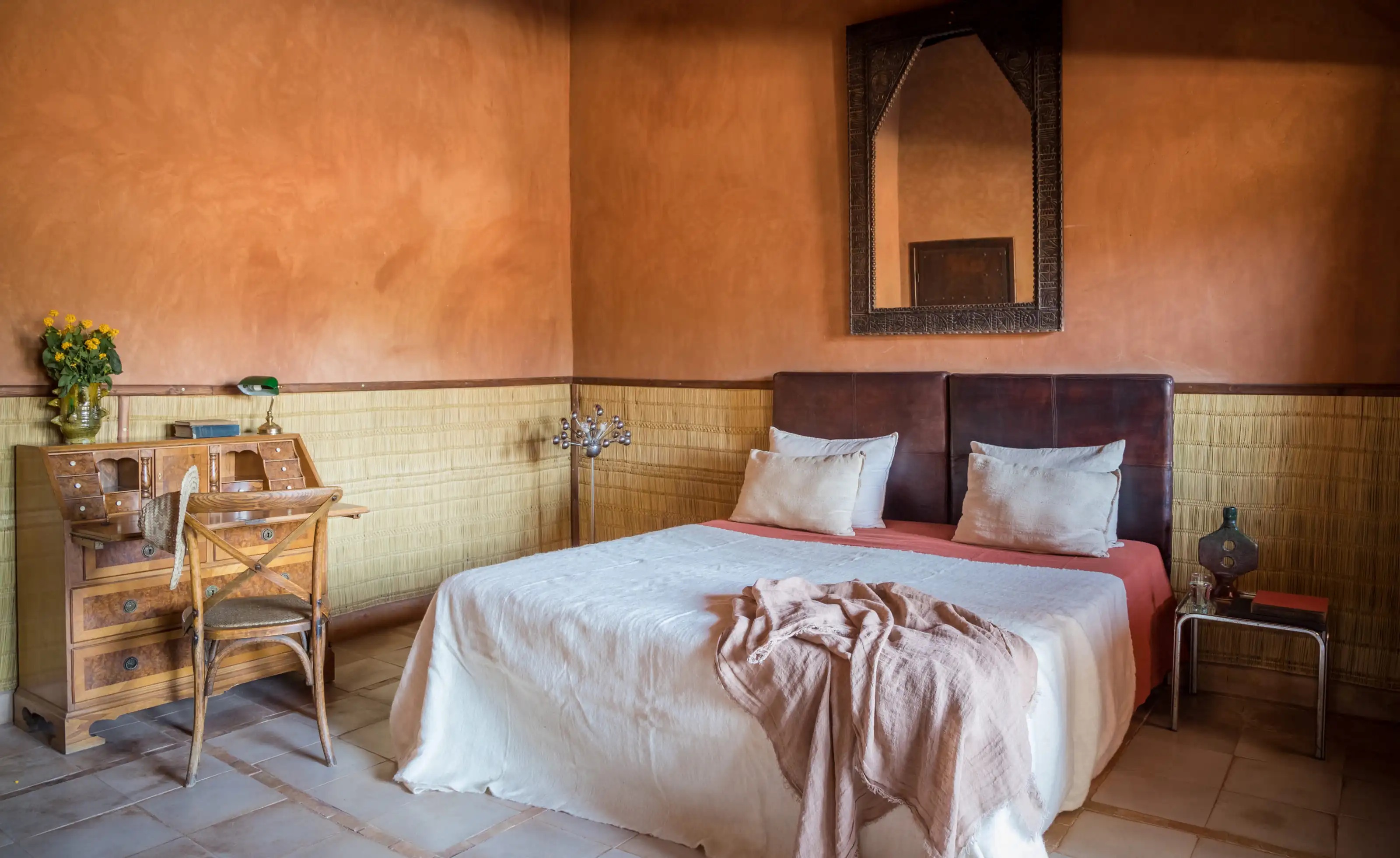 Guest bedroom with warm earthen walls and wooden ceiling at Kasbah Bab Ourika, Ourika Valley, Morocco