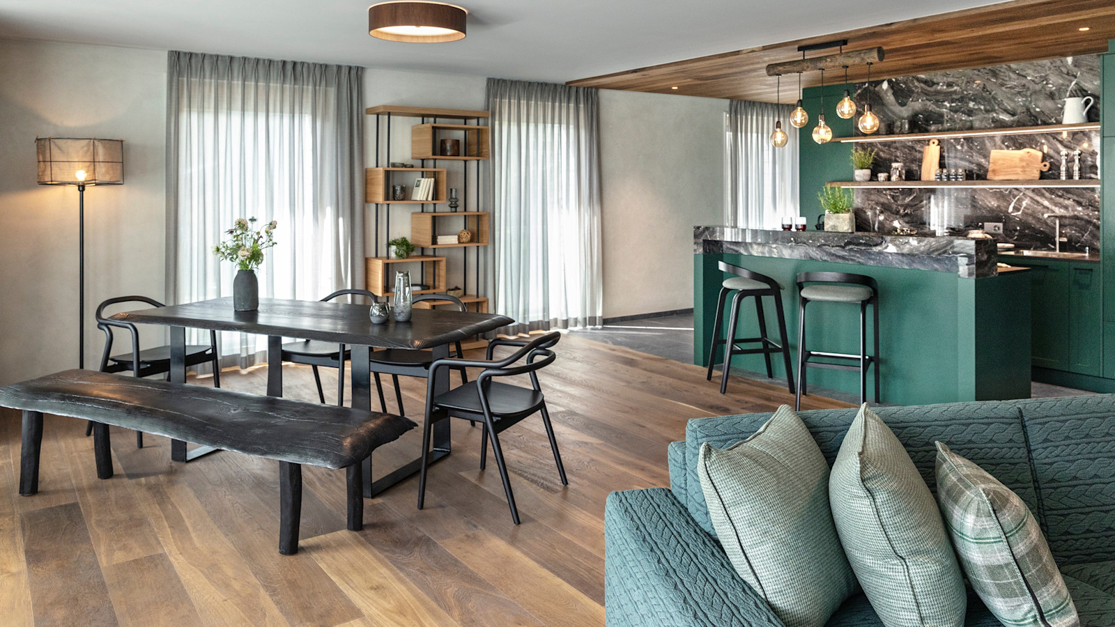 Contemporary living area with dining table and green kitchen island at Tschuggen, Arosa, Switzerland