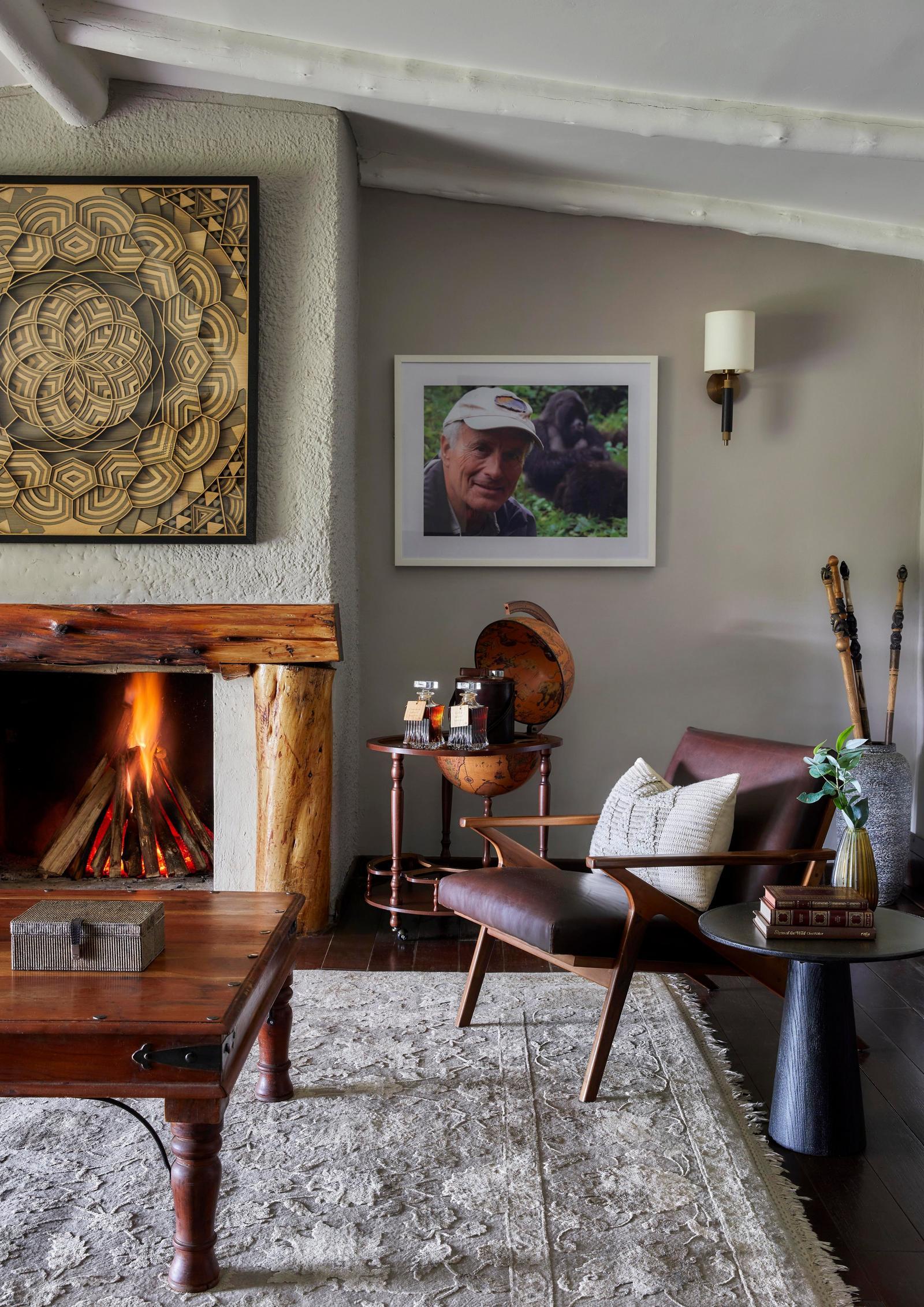 Cottage lounge with a fireplace and patterned armchairs, One&Only Gorilla's Nest, Volcanoes National Park, Rwanda