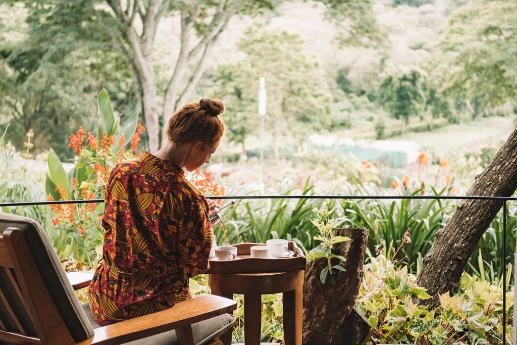 Guest seated on a shaded veranda overlooking the garden at Gibb's Farm.